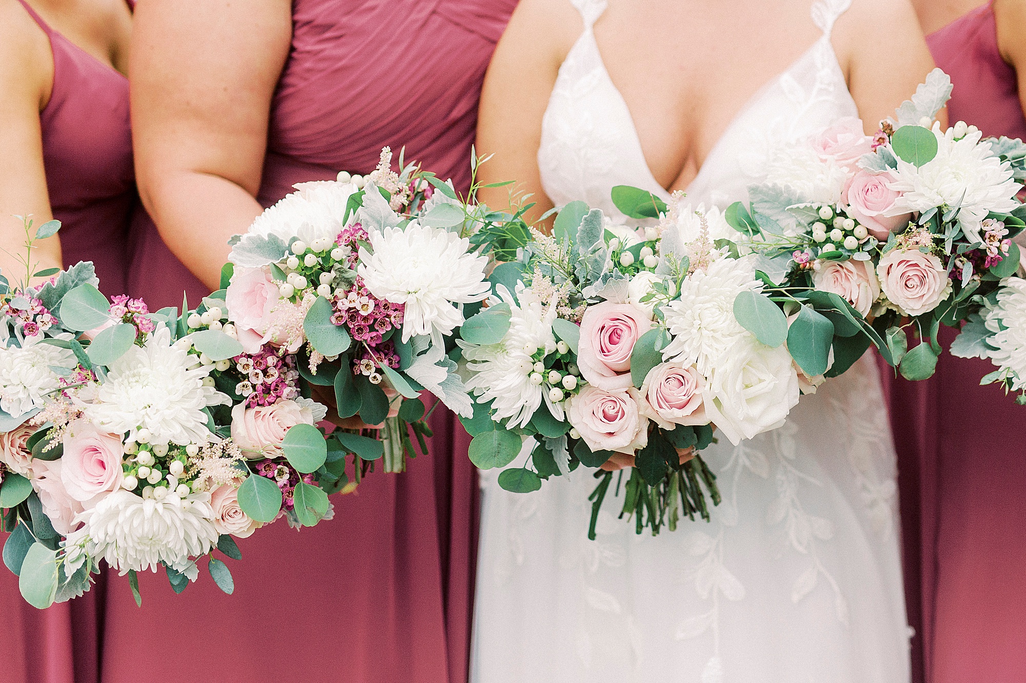 bride and bridesmaids hold pink and ivory flowers
