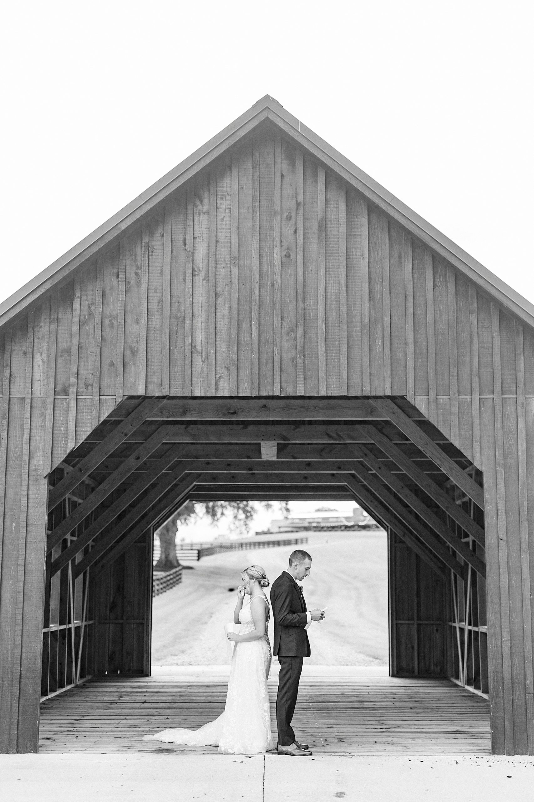 bride and groom stand under covered bridge reading vows on wedding day