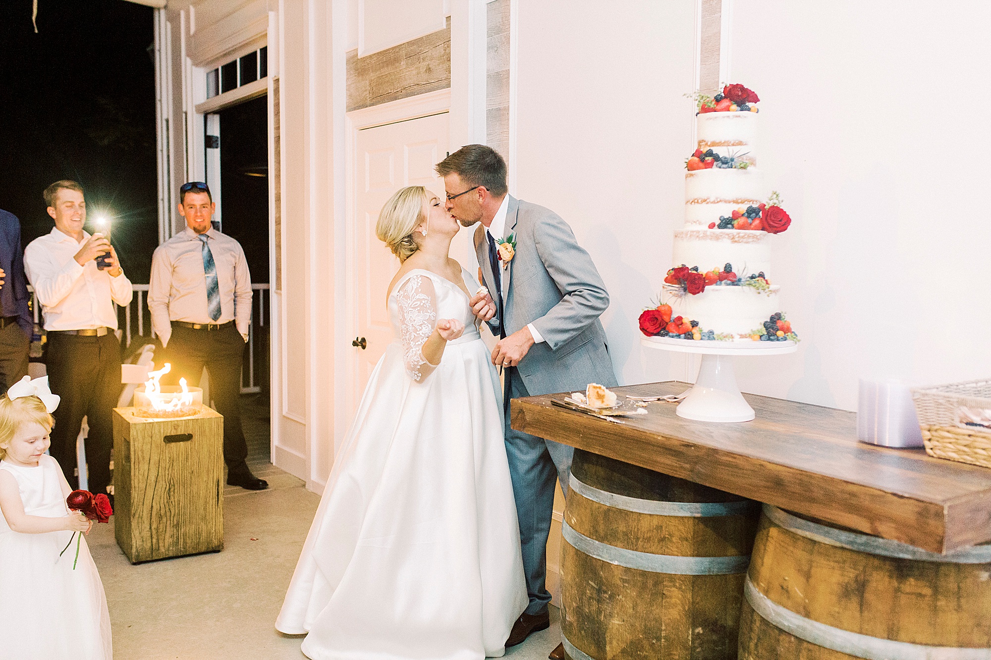 couple kisses during cake cutting during NC wedding reception