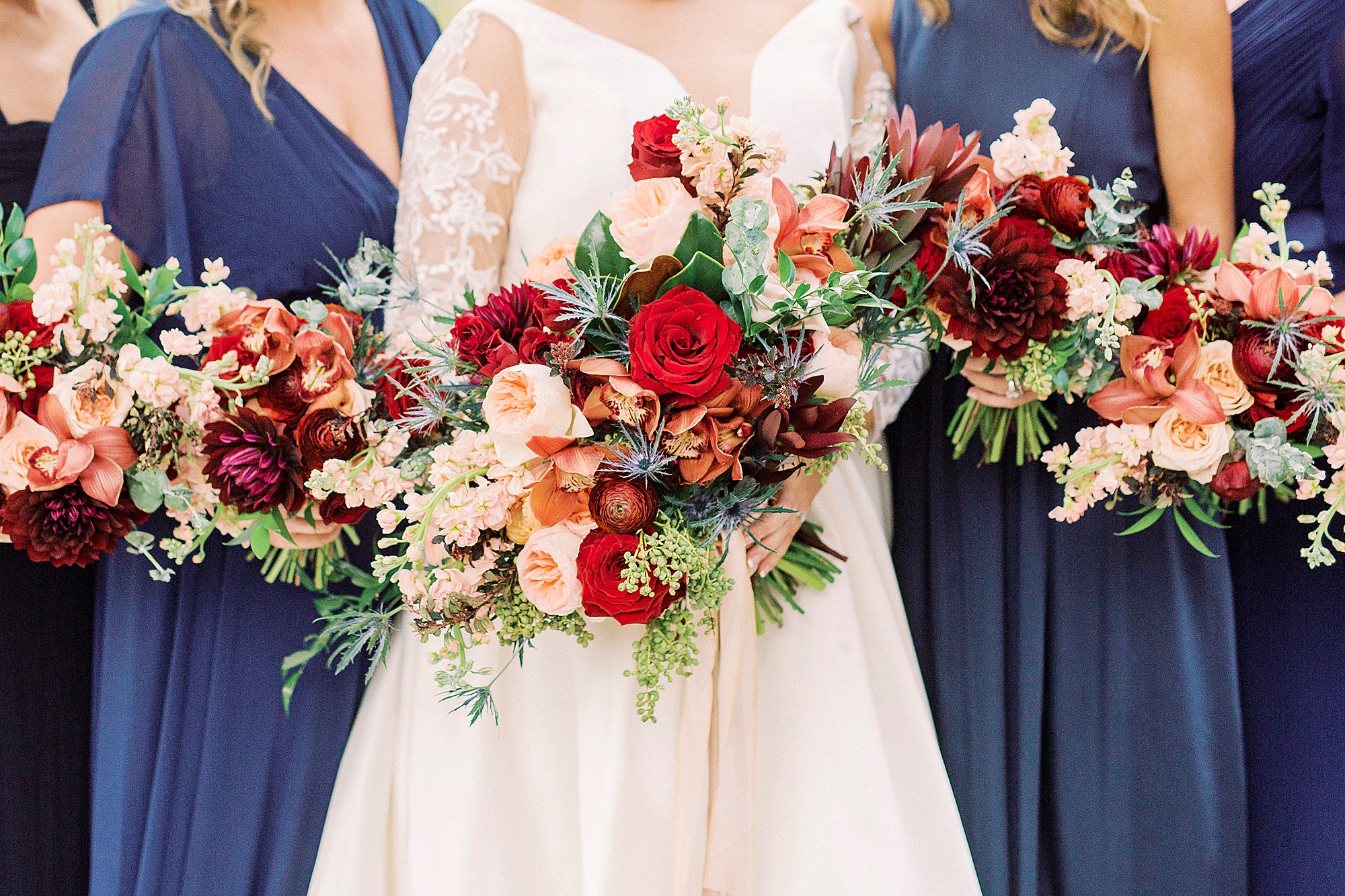 bridesmaids hold bouquets of pink and red flowers for fall wedding