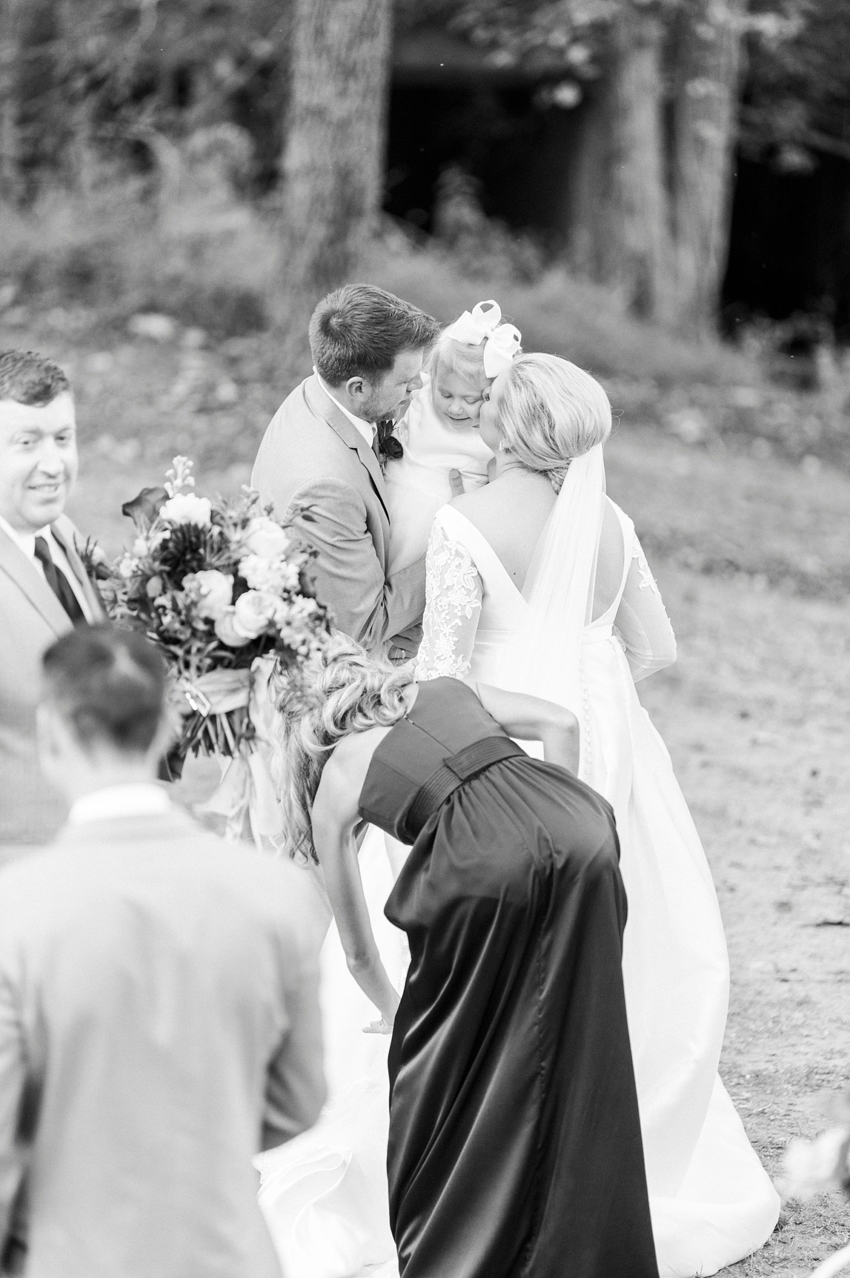 couple hugs daughter during NC wedding ceremony at vineyard