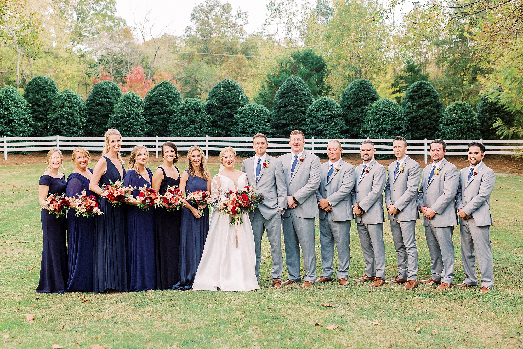 bride and groom stand with wedding party in navy and grey