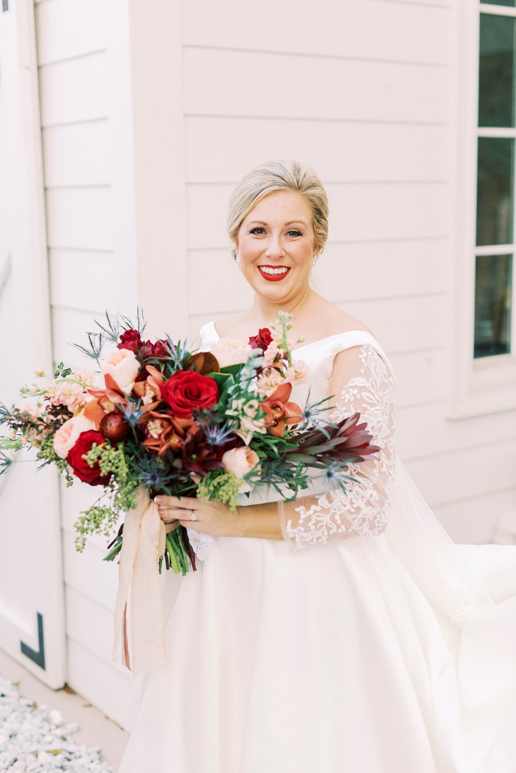 bride holds bouquet of red and peach flowers during Vesuvius Vineyards wedding day