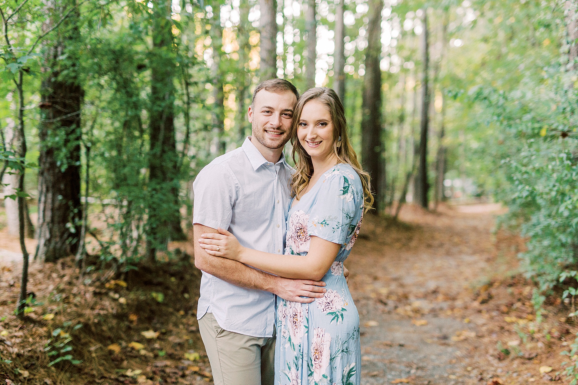 engaged couple stands together on path in Whitewater Center