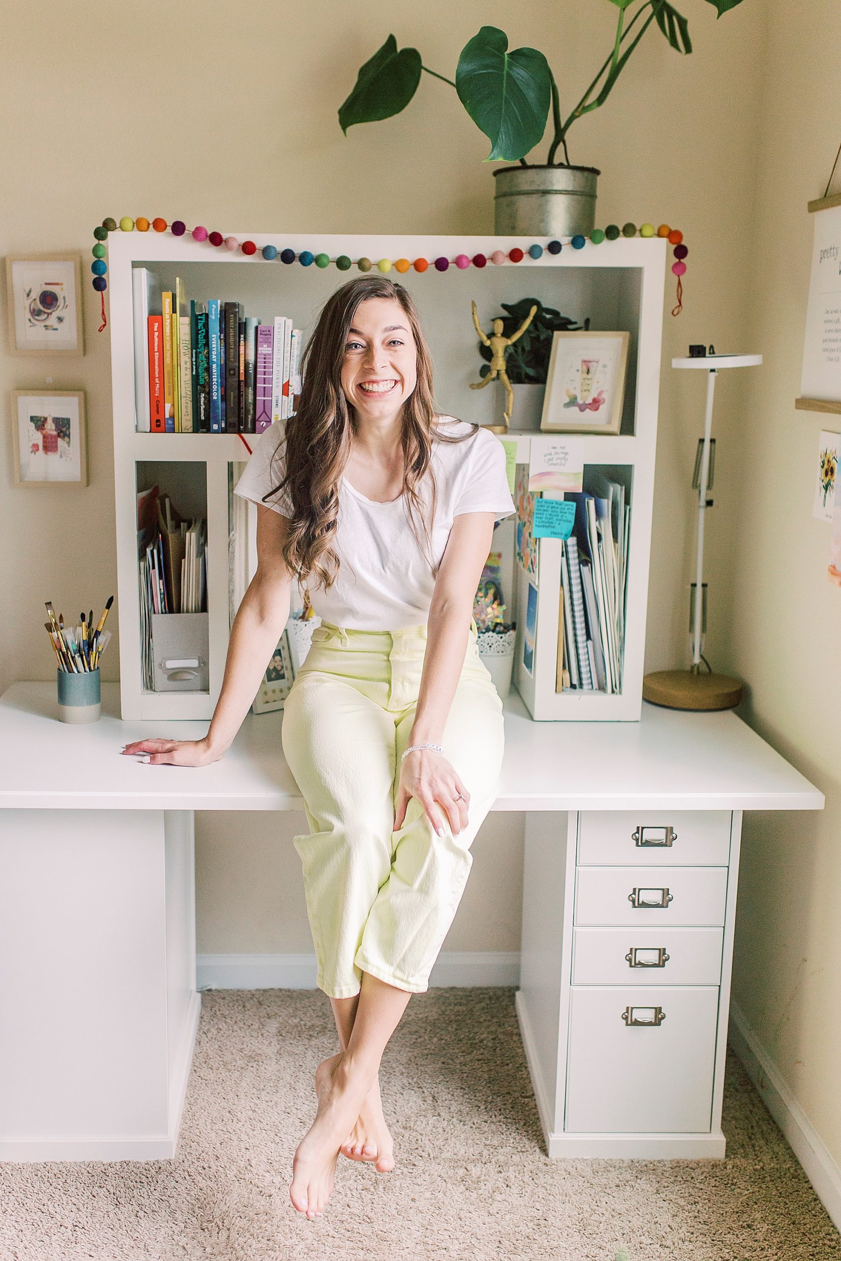 watercolor artist sits on desk during branding photos at home