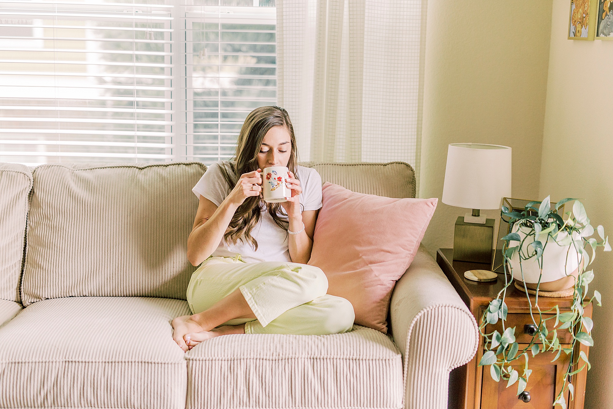 woman sits on couch with coffee mug