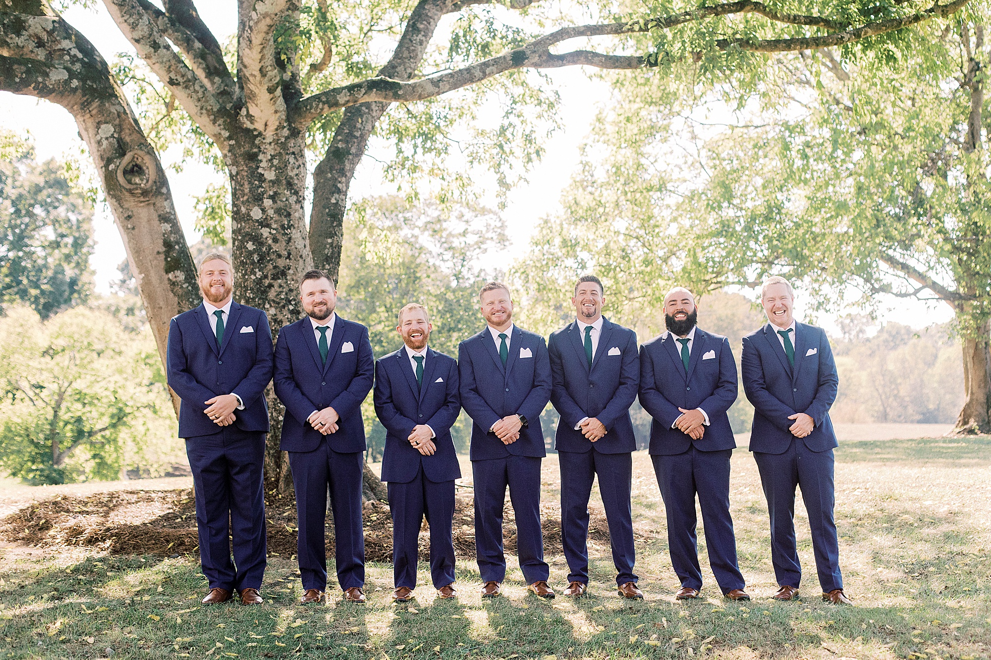 groom stand with groomsmen in navy suits