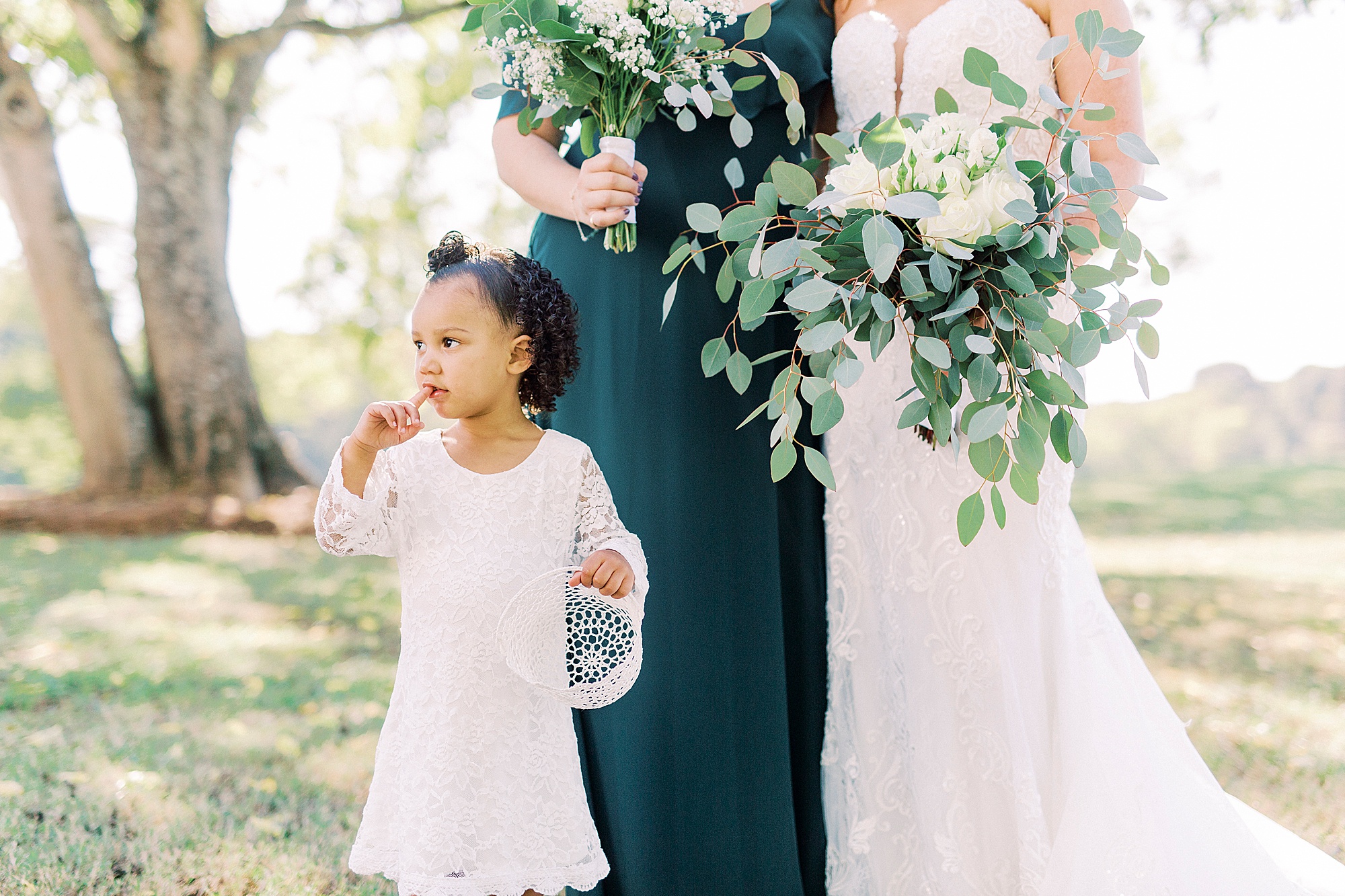 flower girl poses with bridesmaid and bride at The Dairy Barn