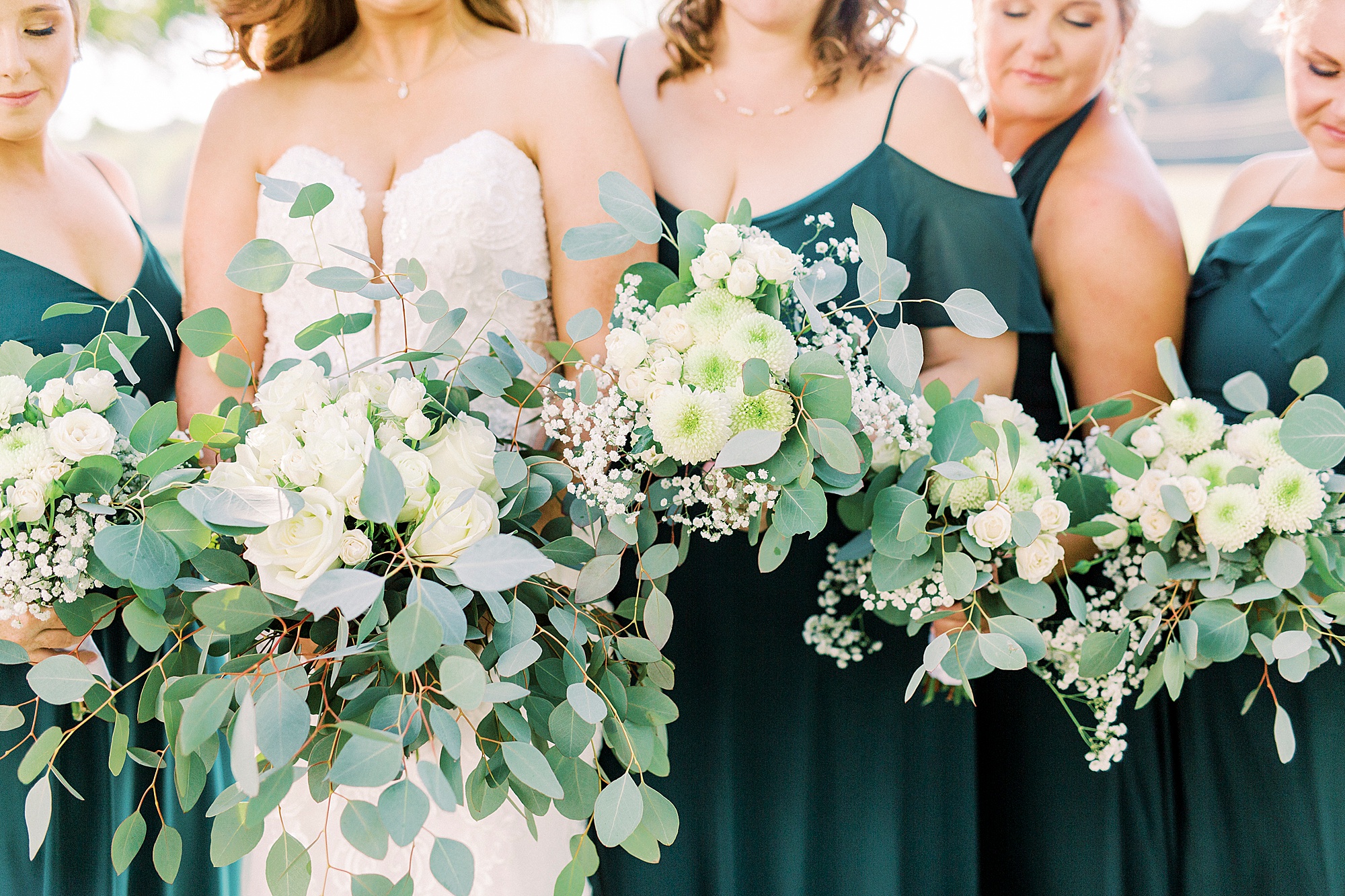 bride and bridesmaids hold white and green floral bouquets