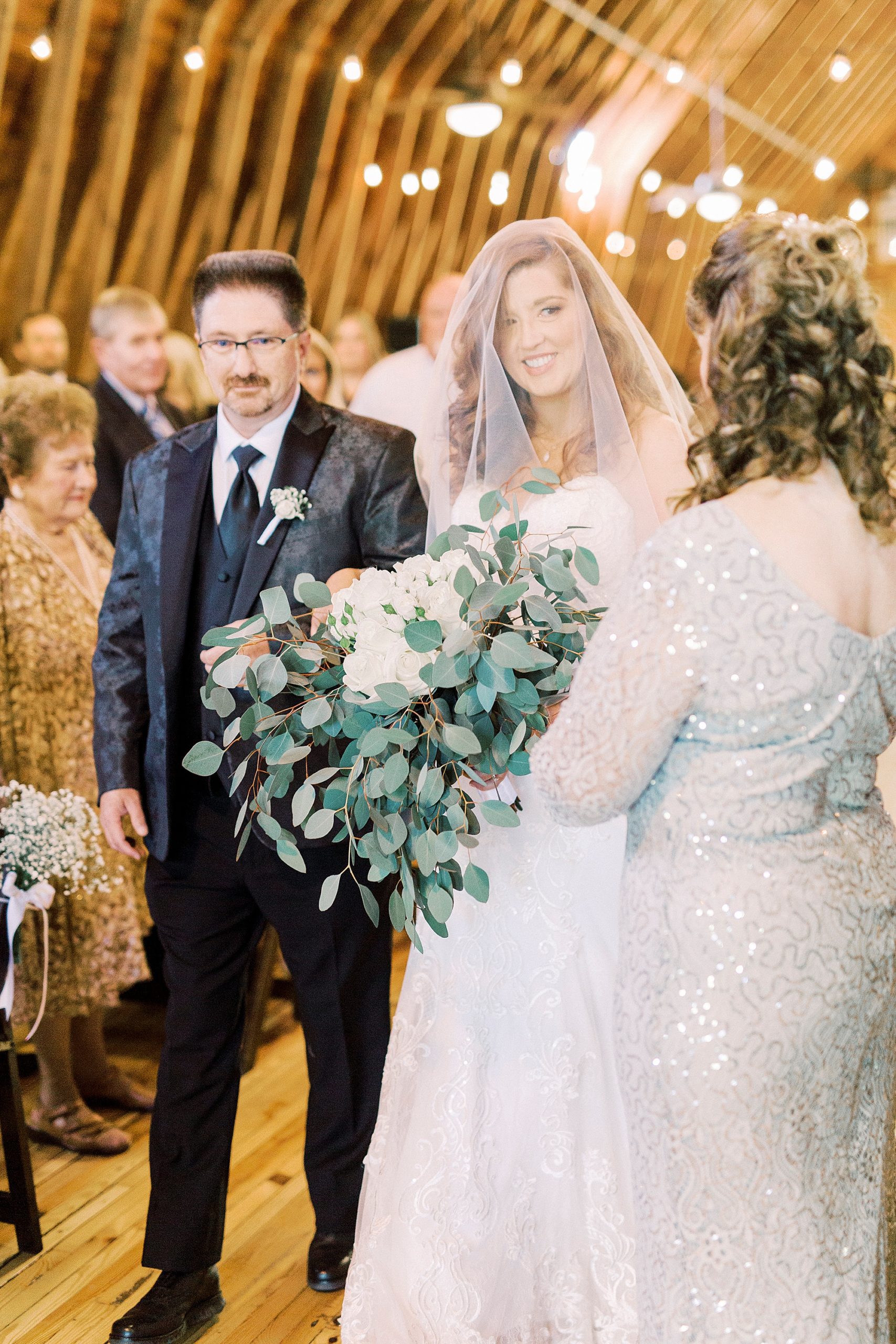 bride smiles at mother walking down aisle