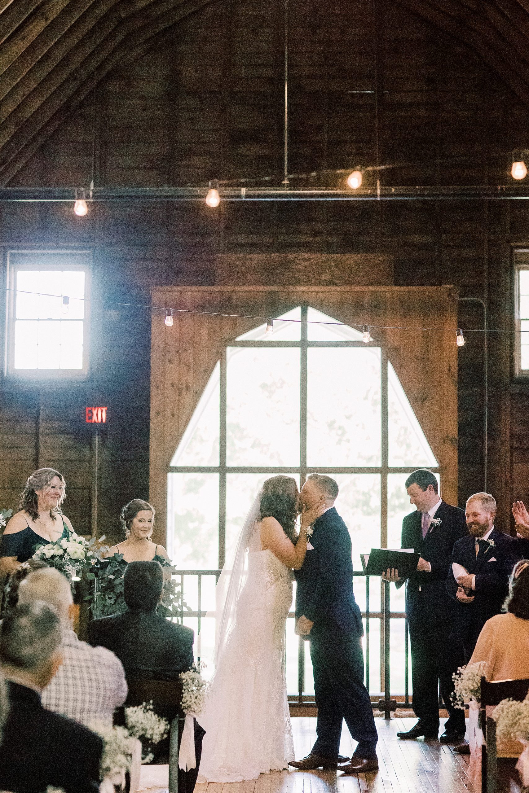 bride and groom kiss during wedding ceremony at The Dairy Barn