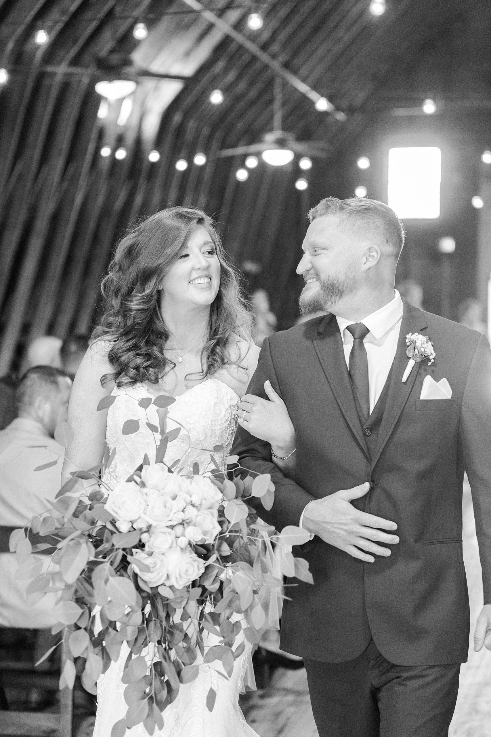 newlyweds smile together walking up aisle at The Dairy Barn