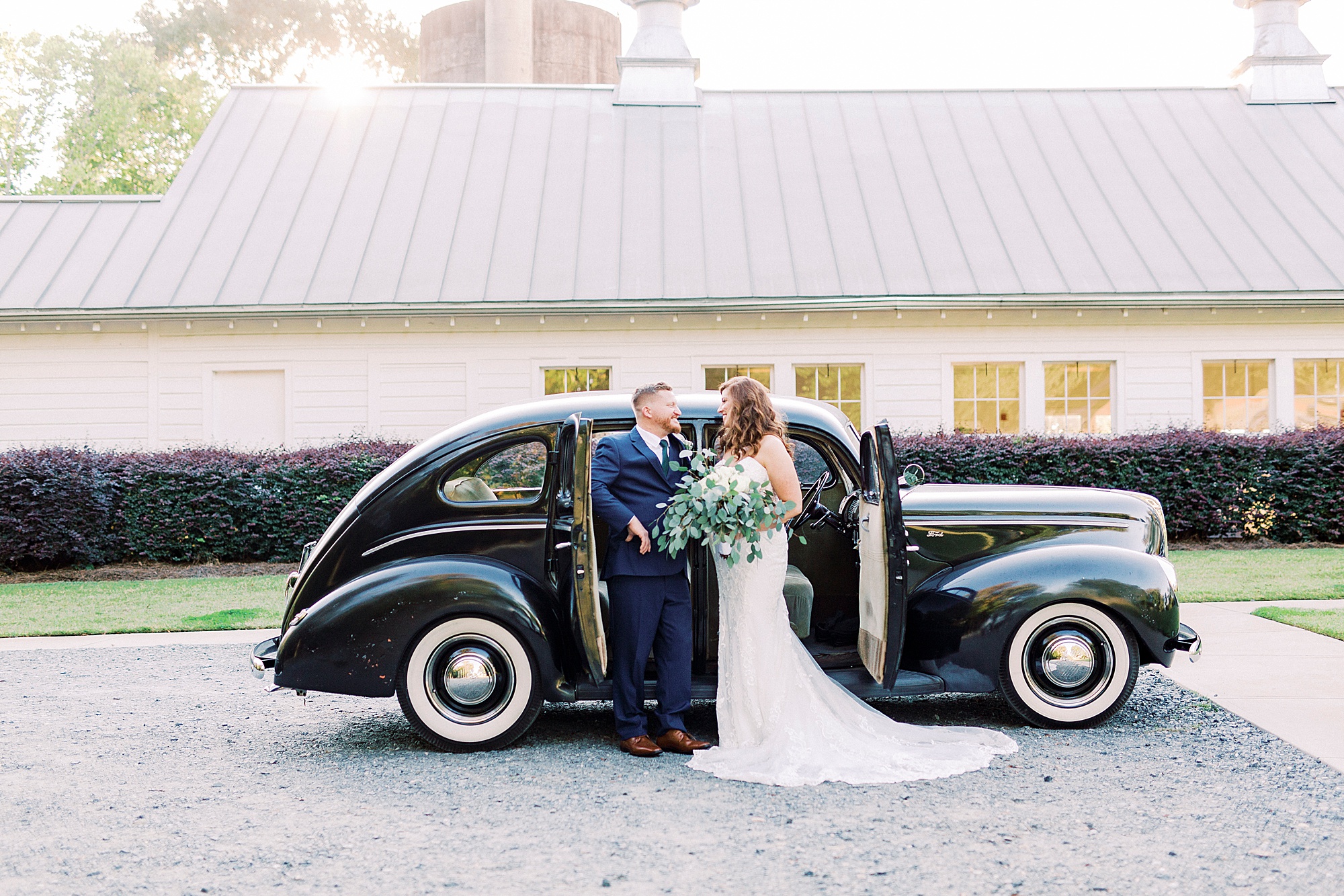 newlyweds pose outside classic black car at The Dairy Barn