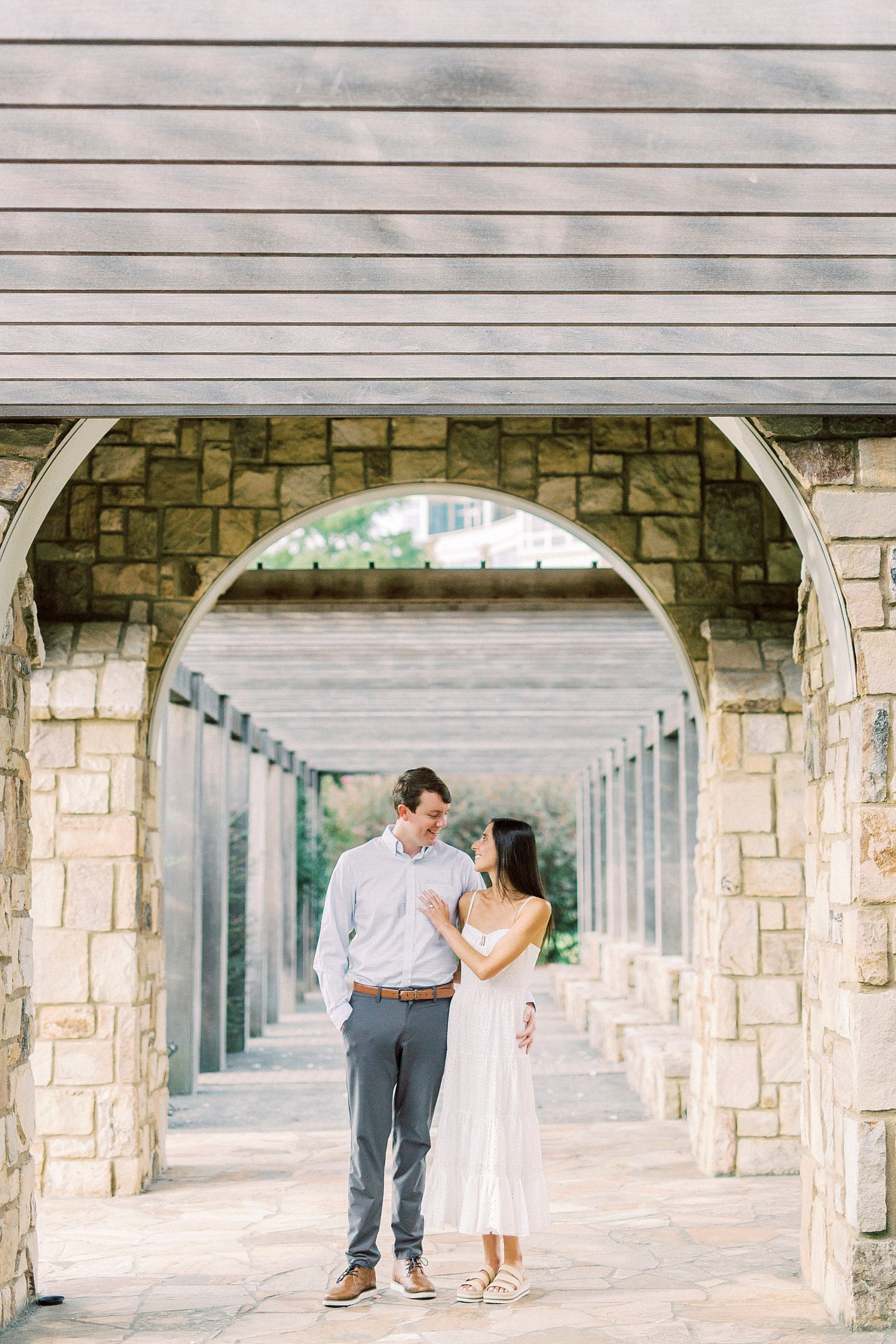 bride and groom walk under stone arbor at Midtown Park