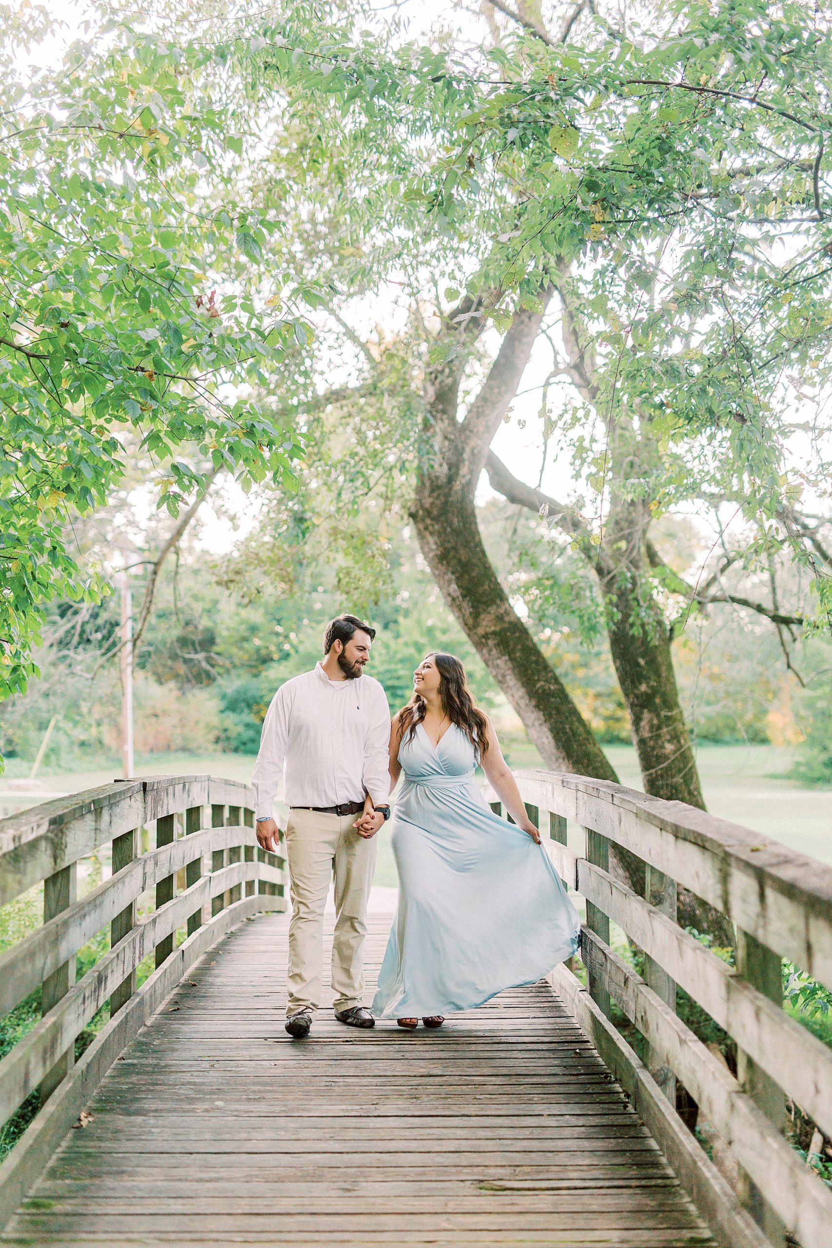 engaged couple walks on wooden bridge during Sloan Park engagement session