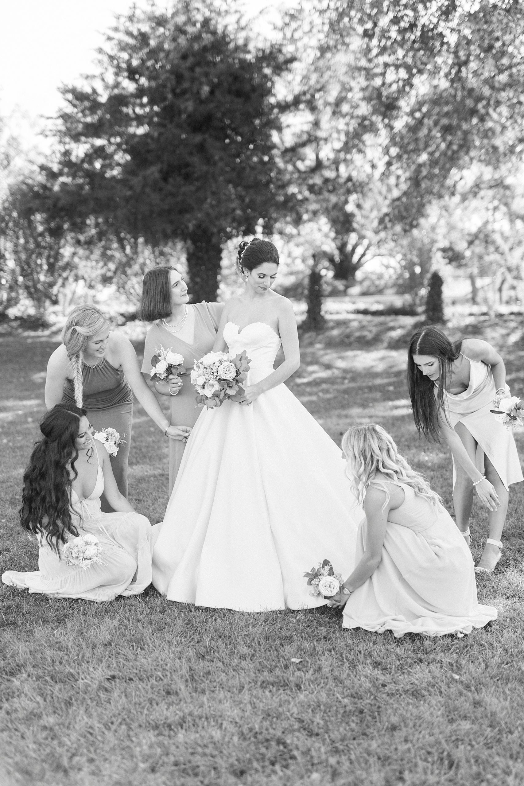 bridesmaids help bride with wedding gown during portraits