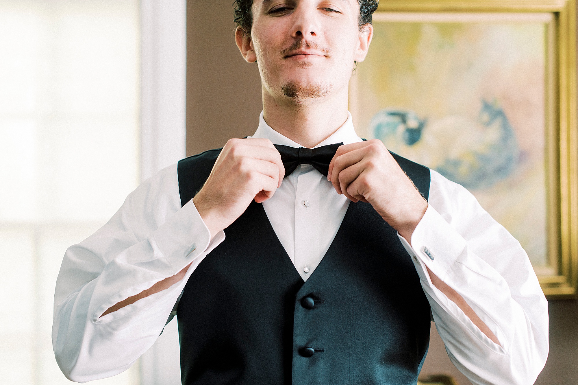 groom adjusts tie before wedding day