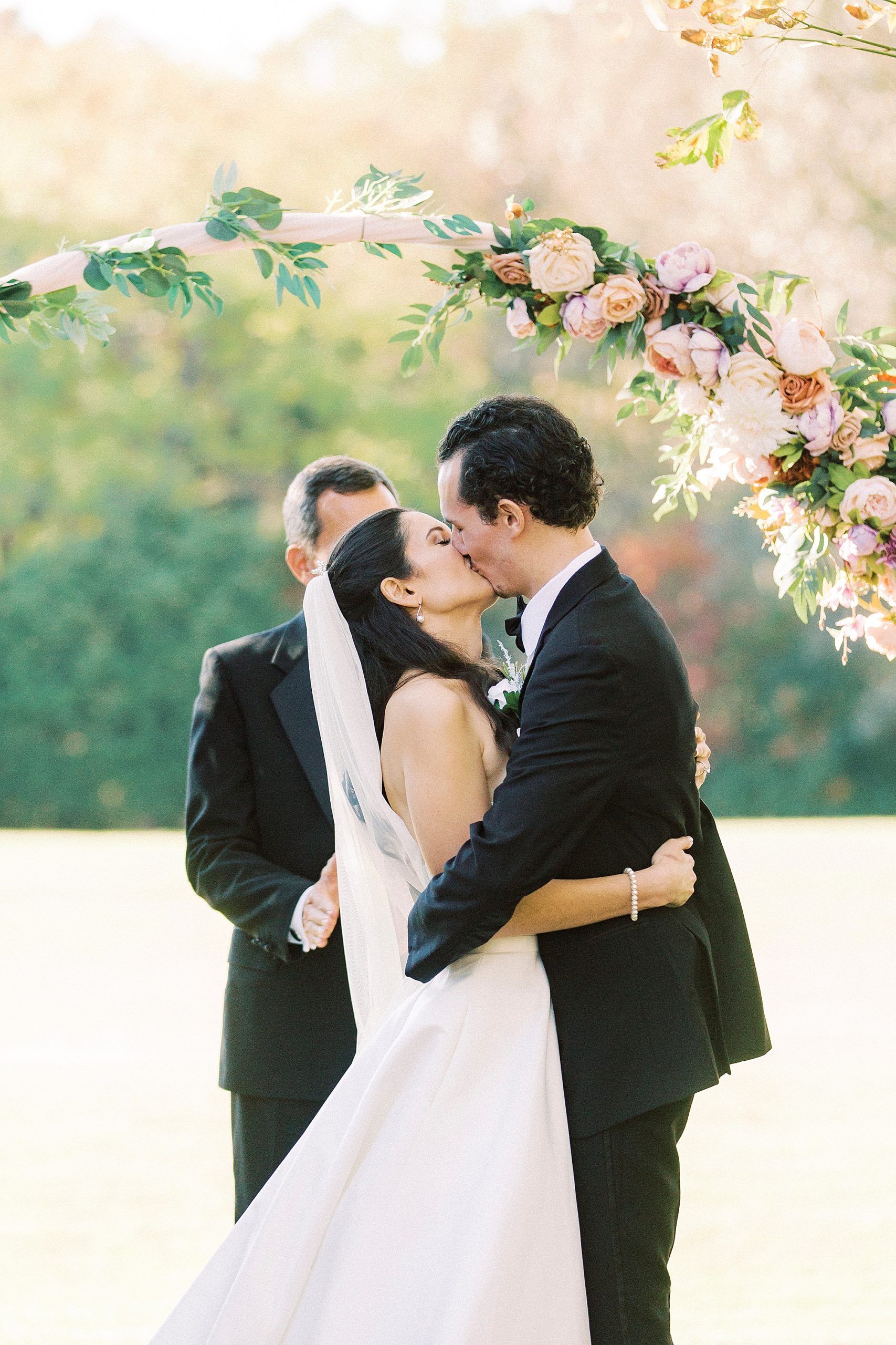 bride and groom kiss during outdoor wedding the spring