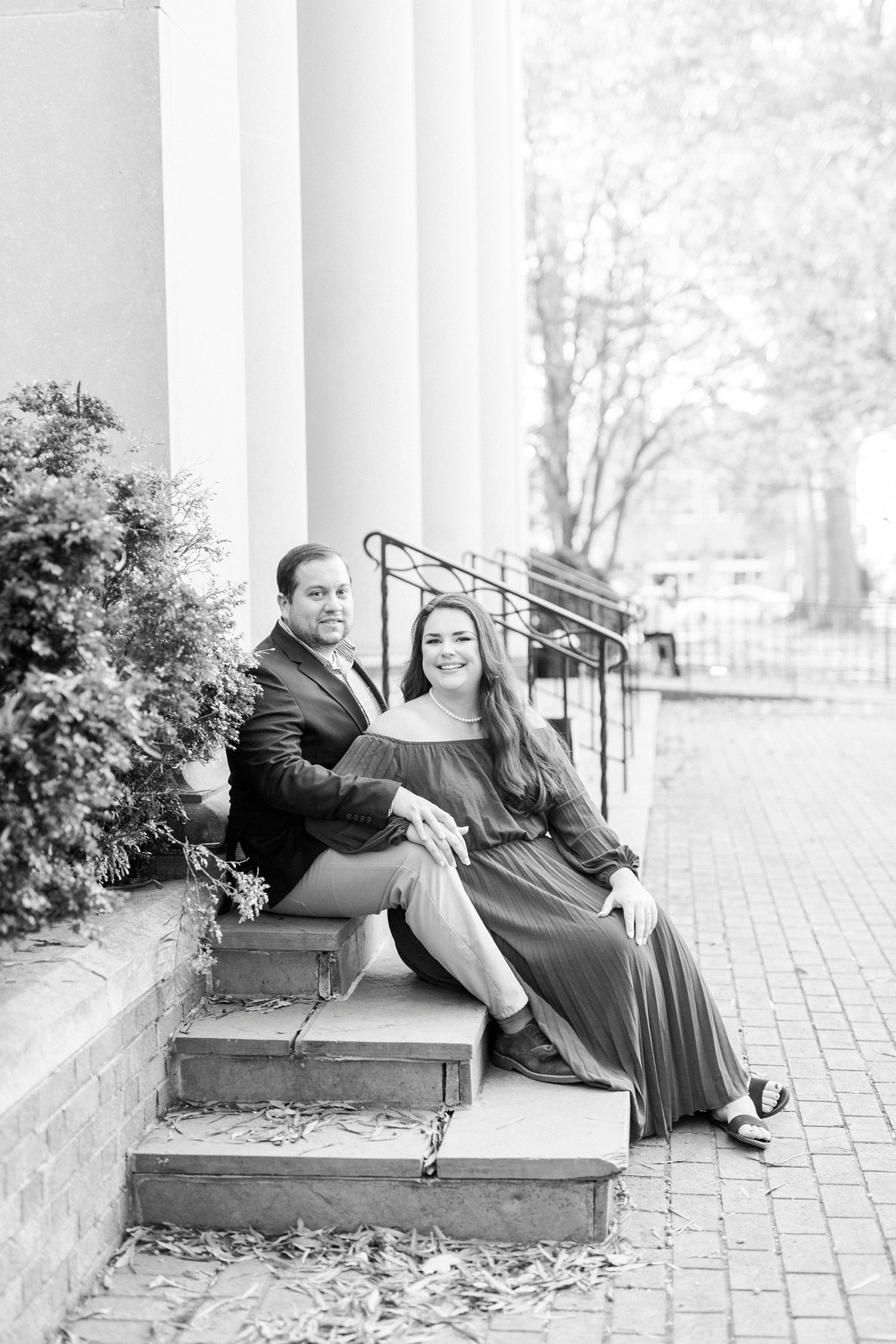 engaged couple sits on steps in Downtown Davidson