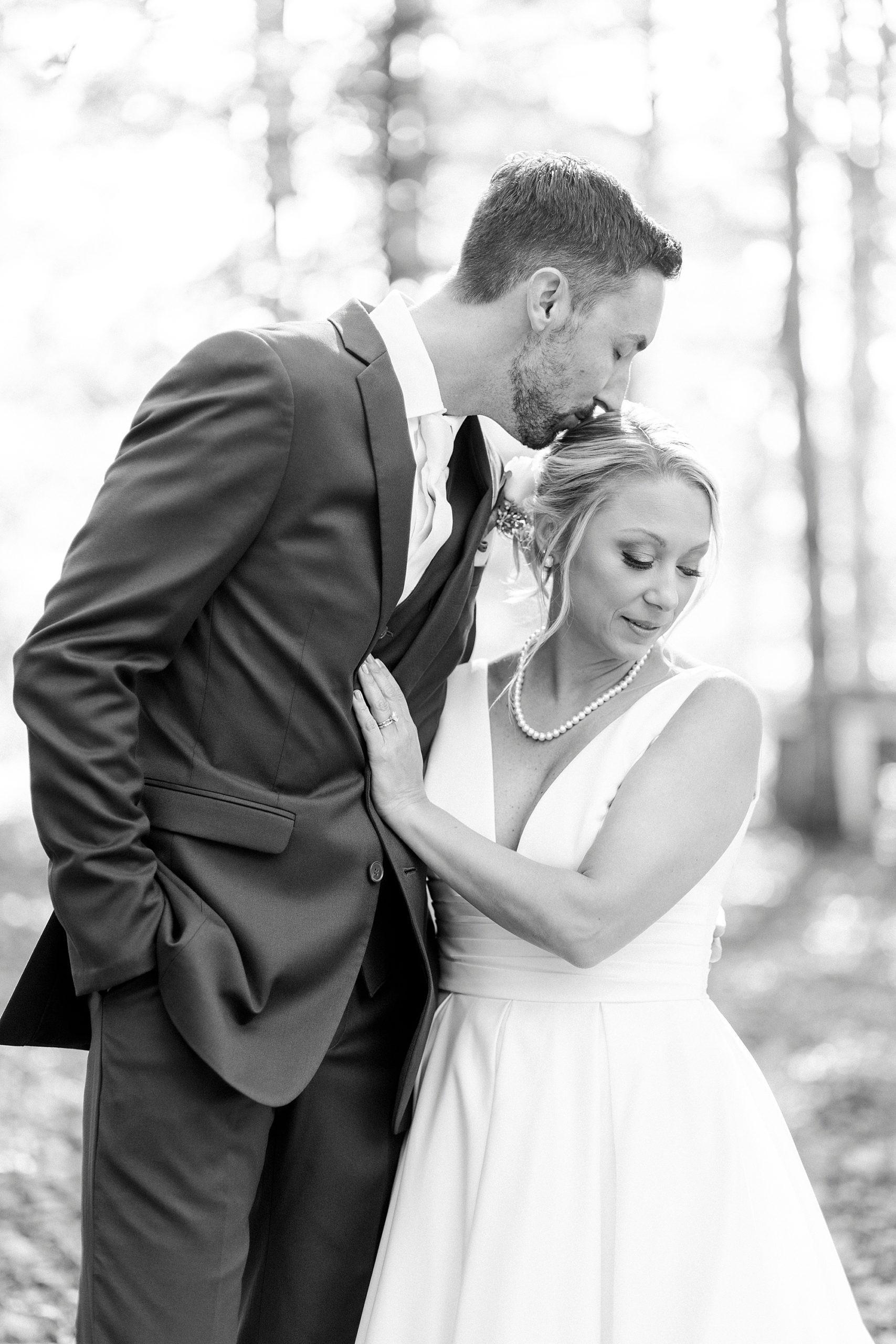 groom leans down to kiss bride's forehead during fall wedding portraits