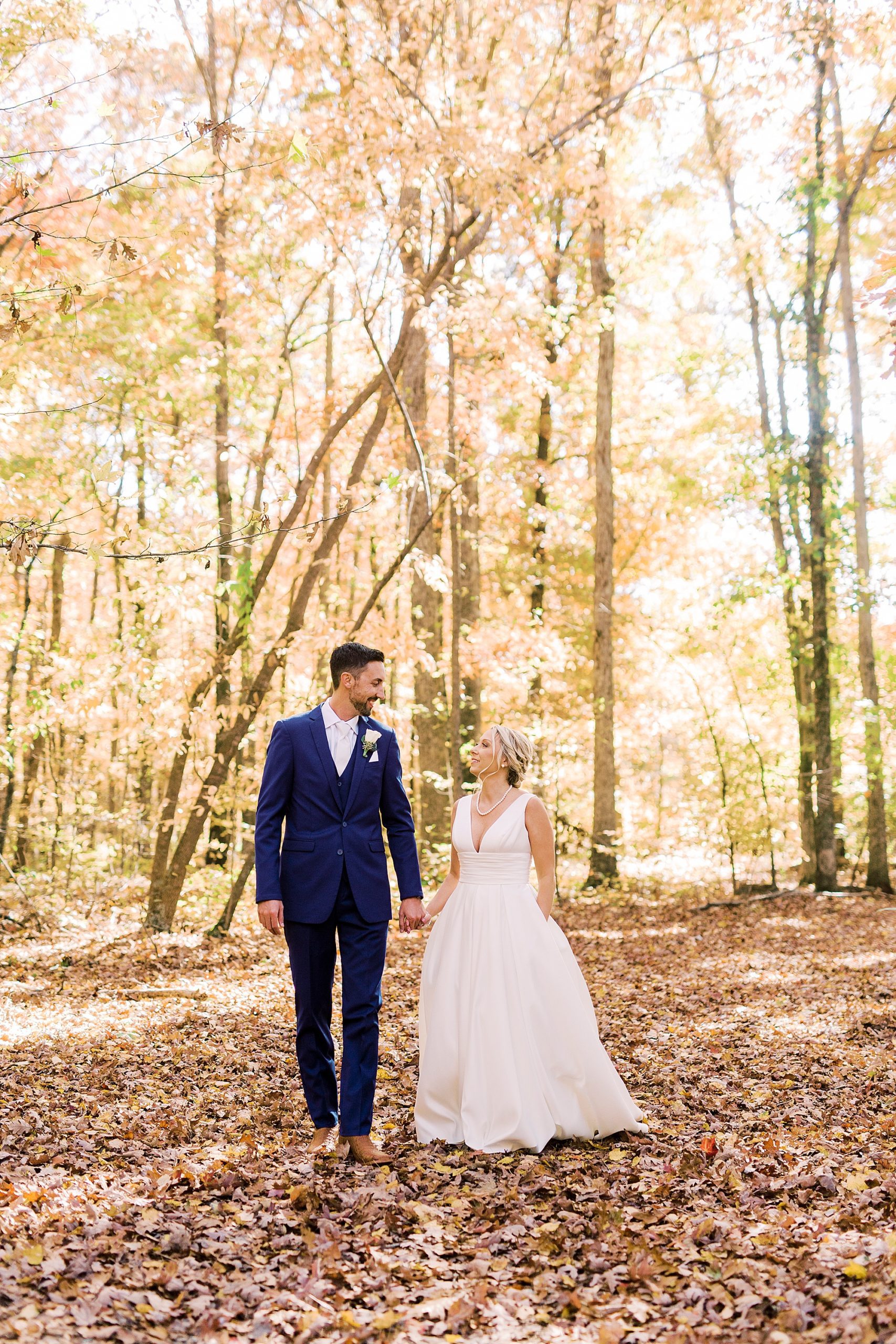 bride and groom hold hands walking through woods before Farm at Brusharbor wedding
