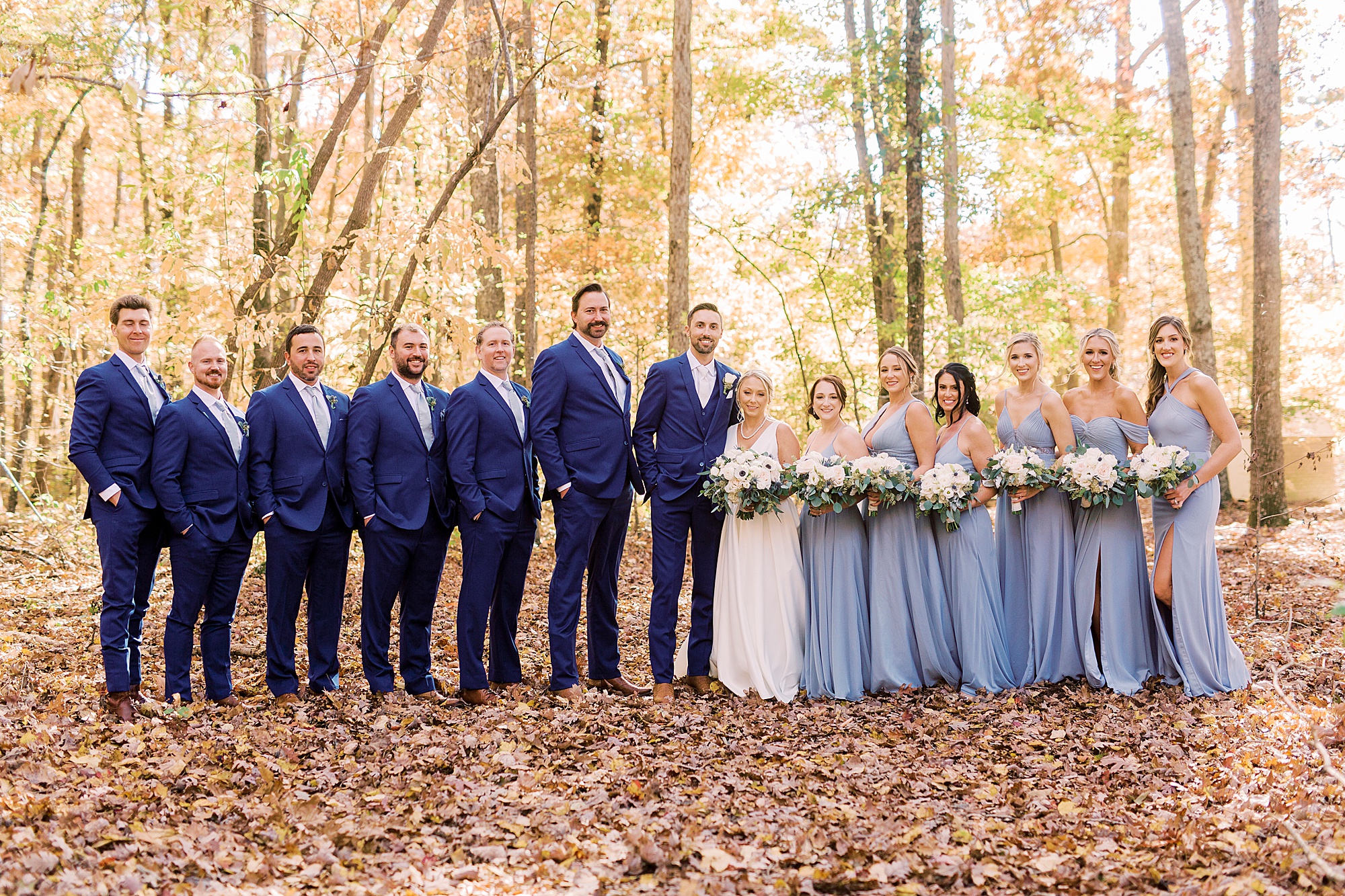 bride and groom pose with wedding party in pastel blue and navy suits