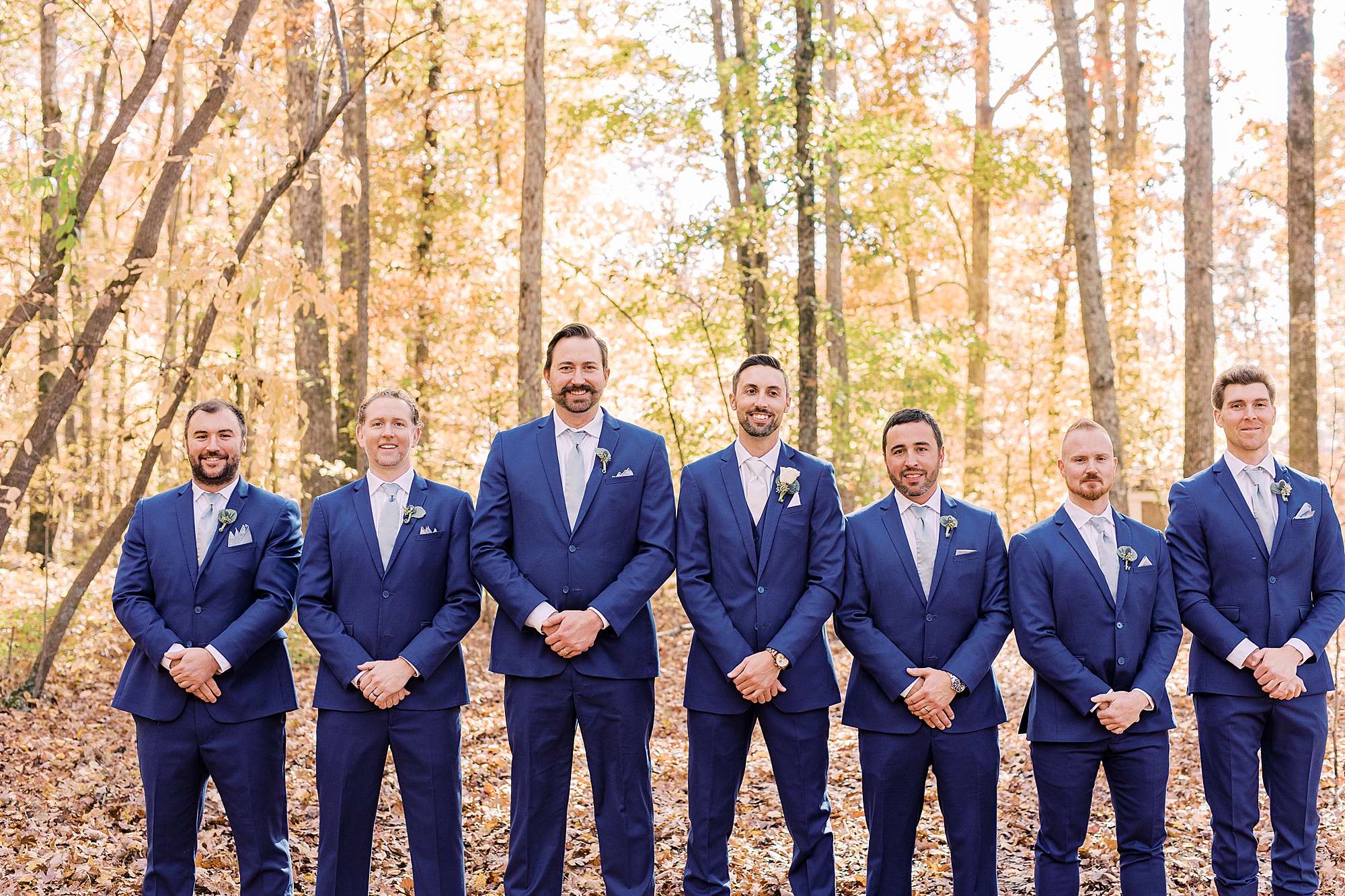 groom stand with groomsmen in navy blue suits