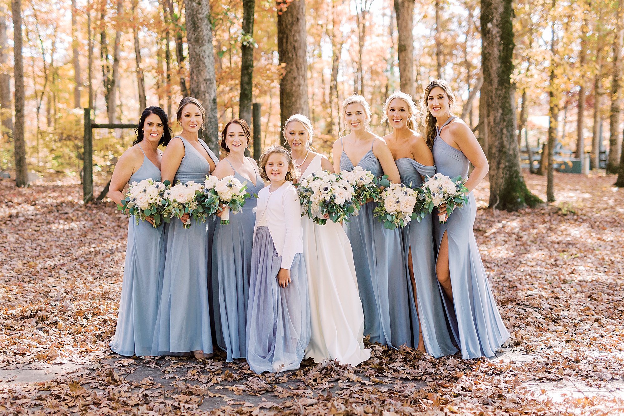 bride stands with bridesmaids in pastel blue gowns