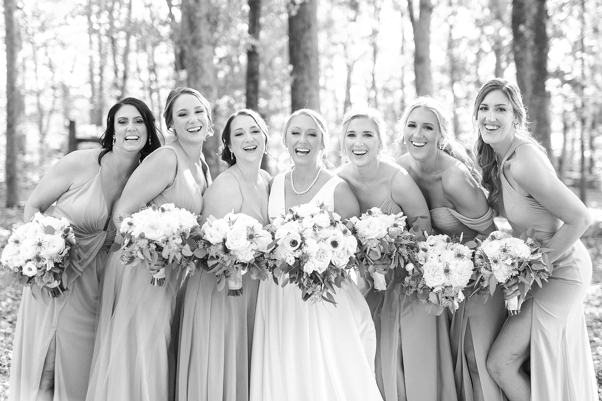 bride poses with bridesmaids holding white bouquets at Farm at Brusharbor