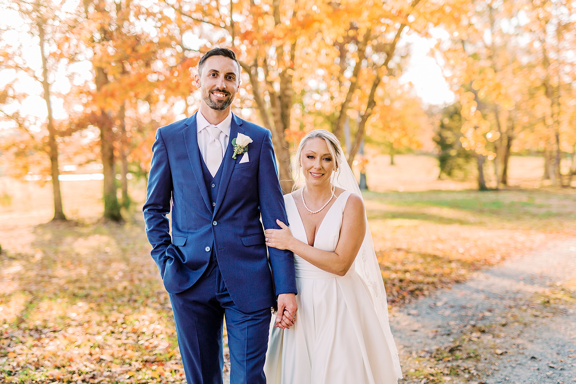 bride and groom hold hands during fall wedding portraits
