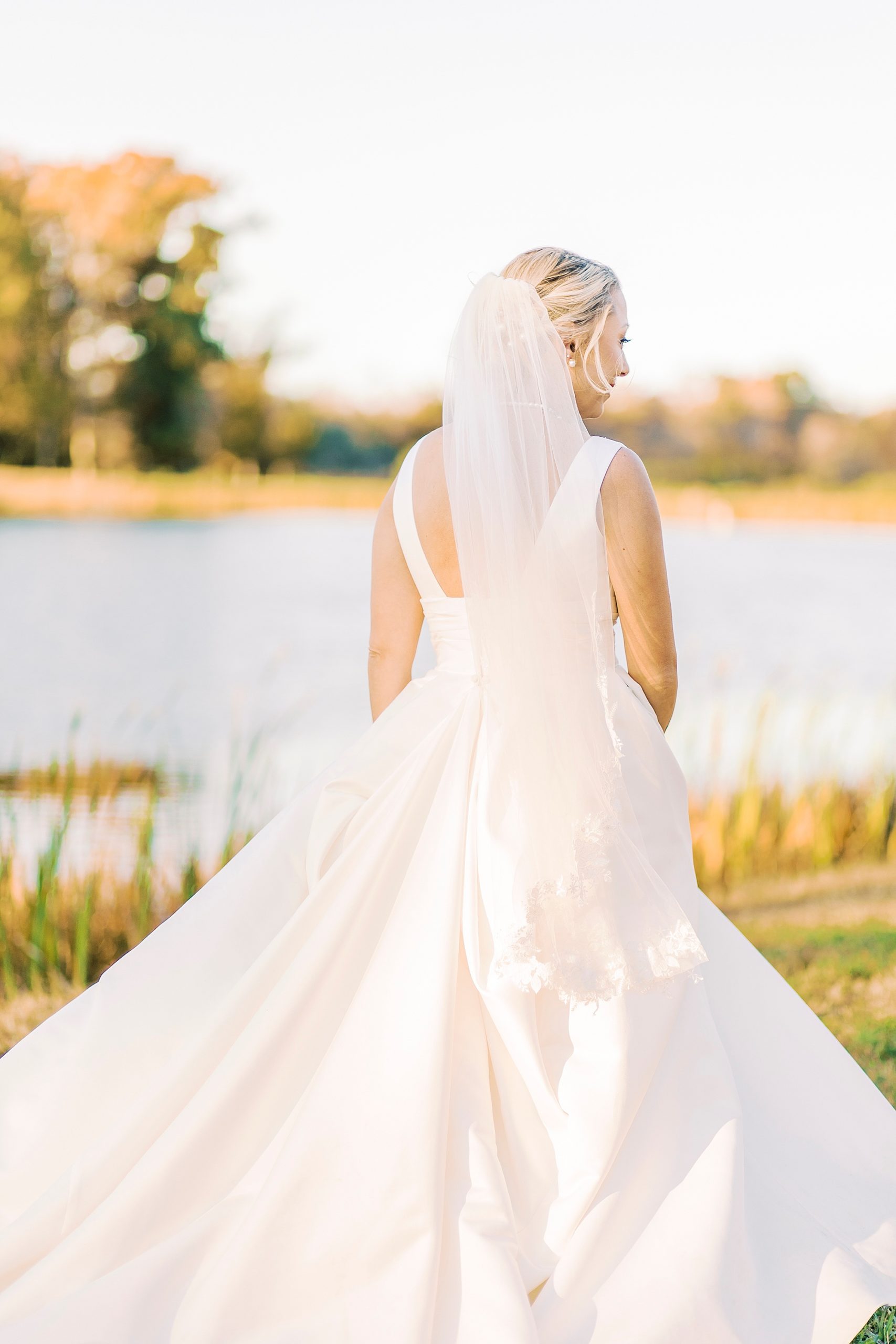 bride poses with back of dress showing and veil floating