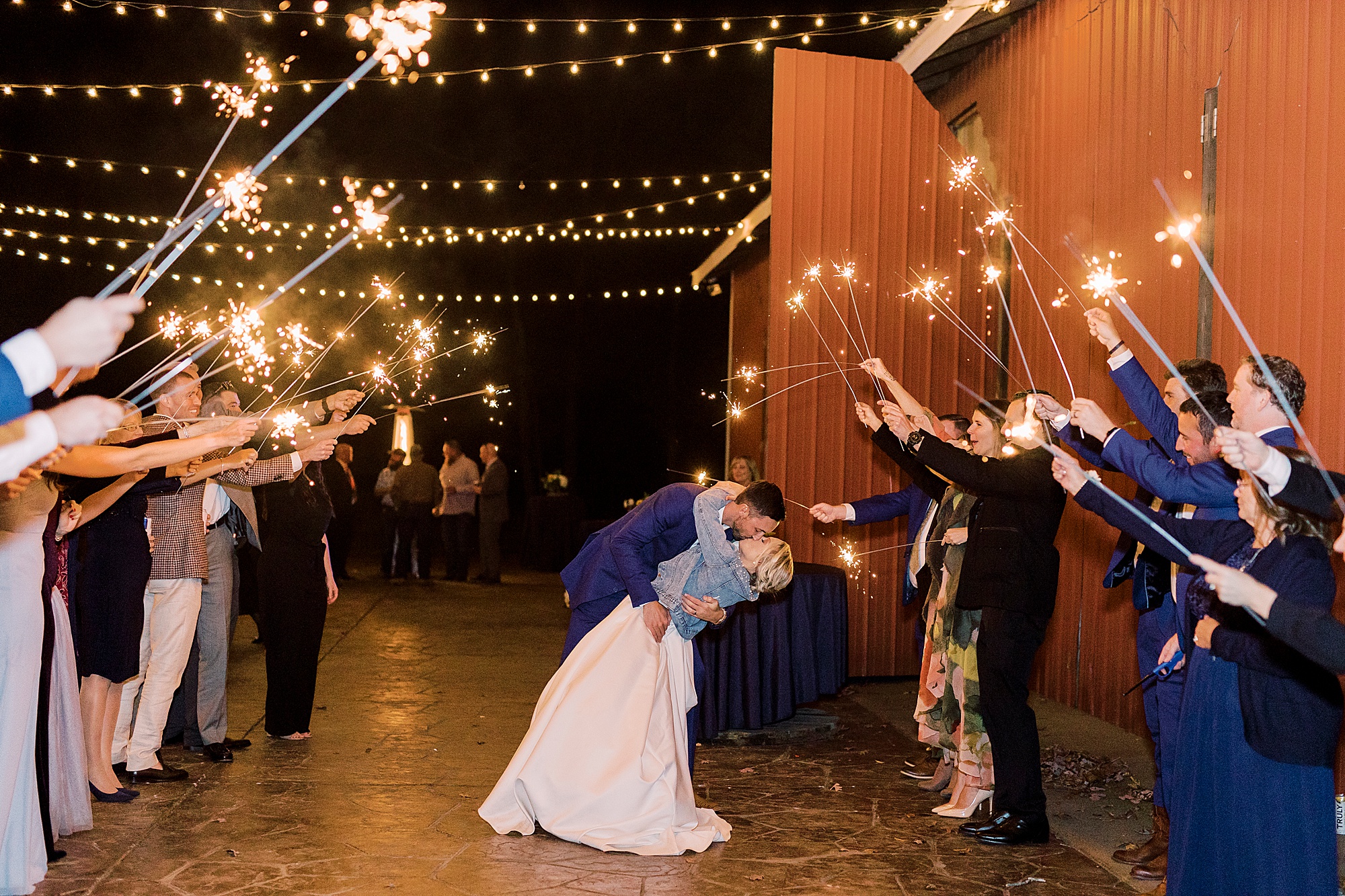 groom dips bride kissing her during sparkler exit