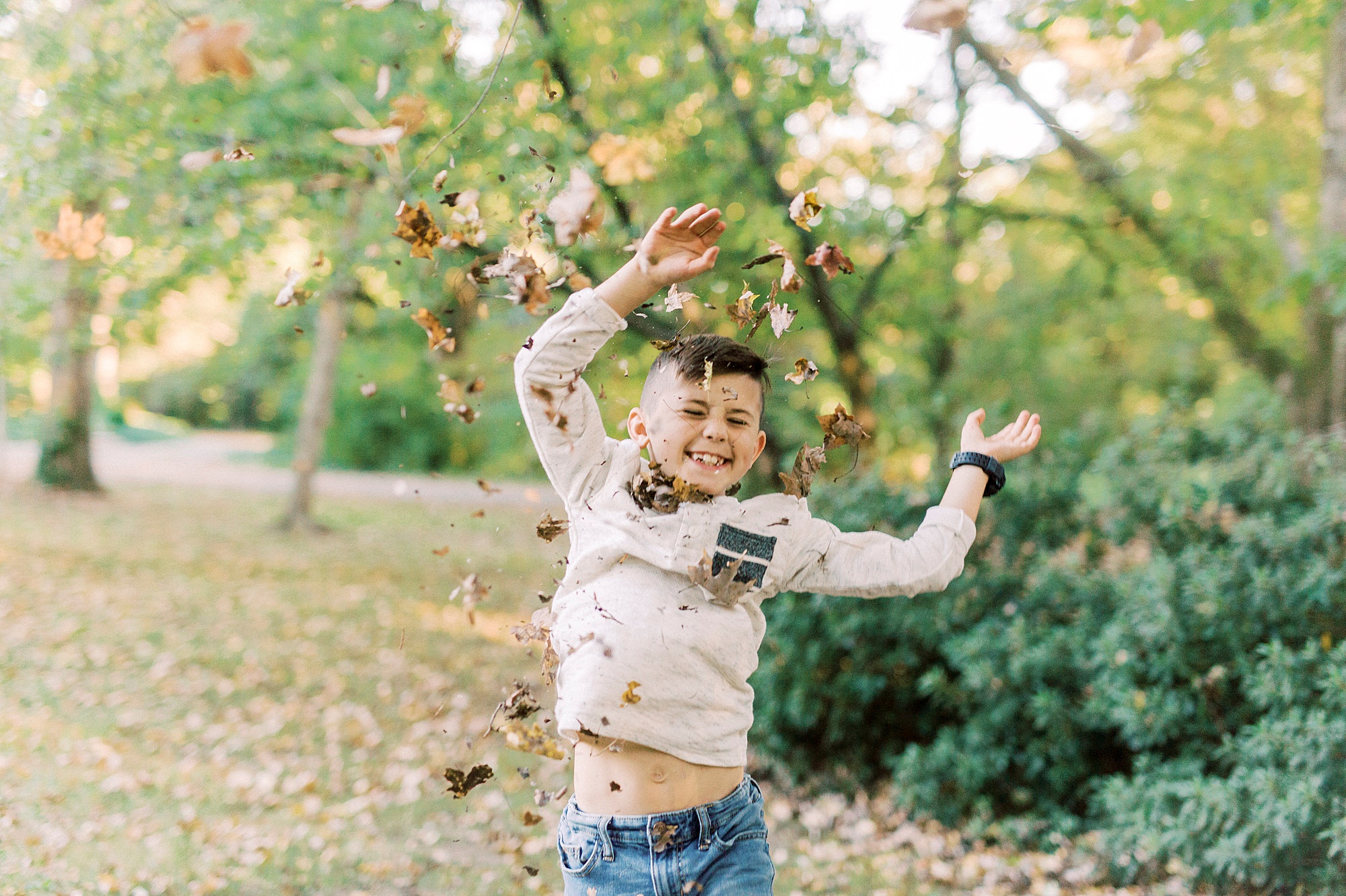 boy tosses leaves during fall photos at Ritchie Hill