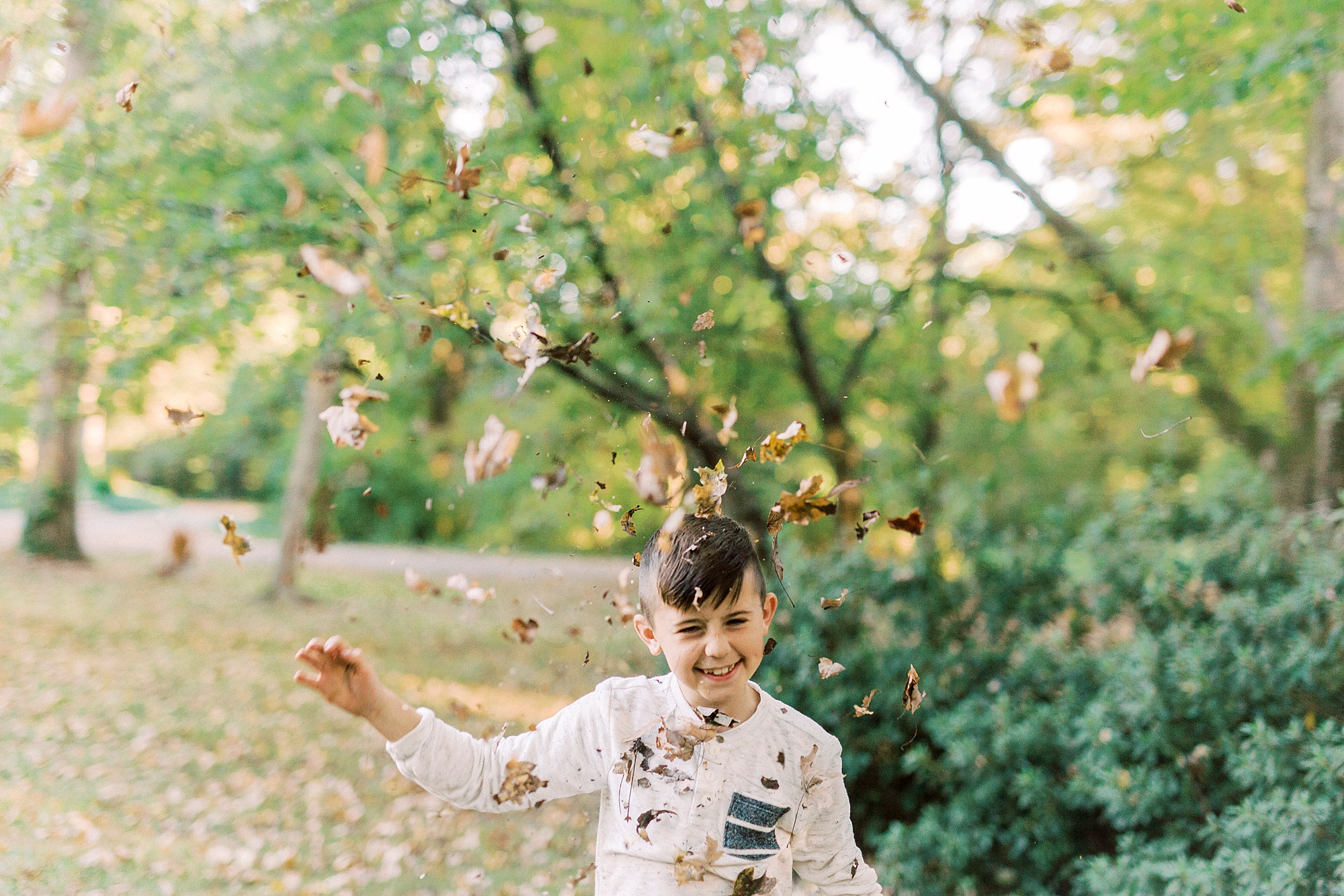 boy tosses leaves during fall family photos in NC