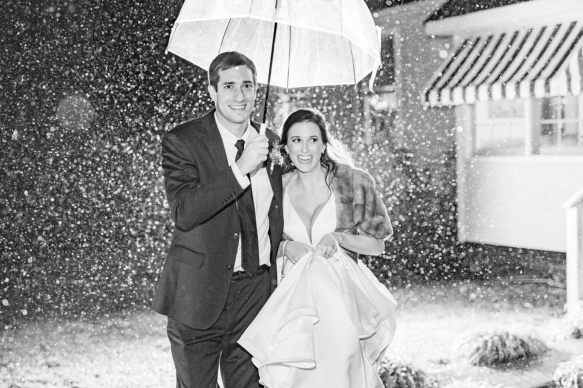 bride and groom laugh running through rain on wedding day