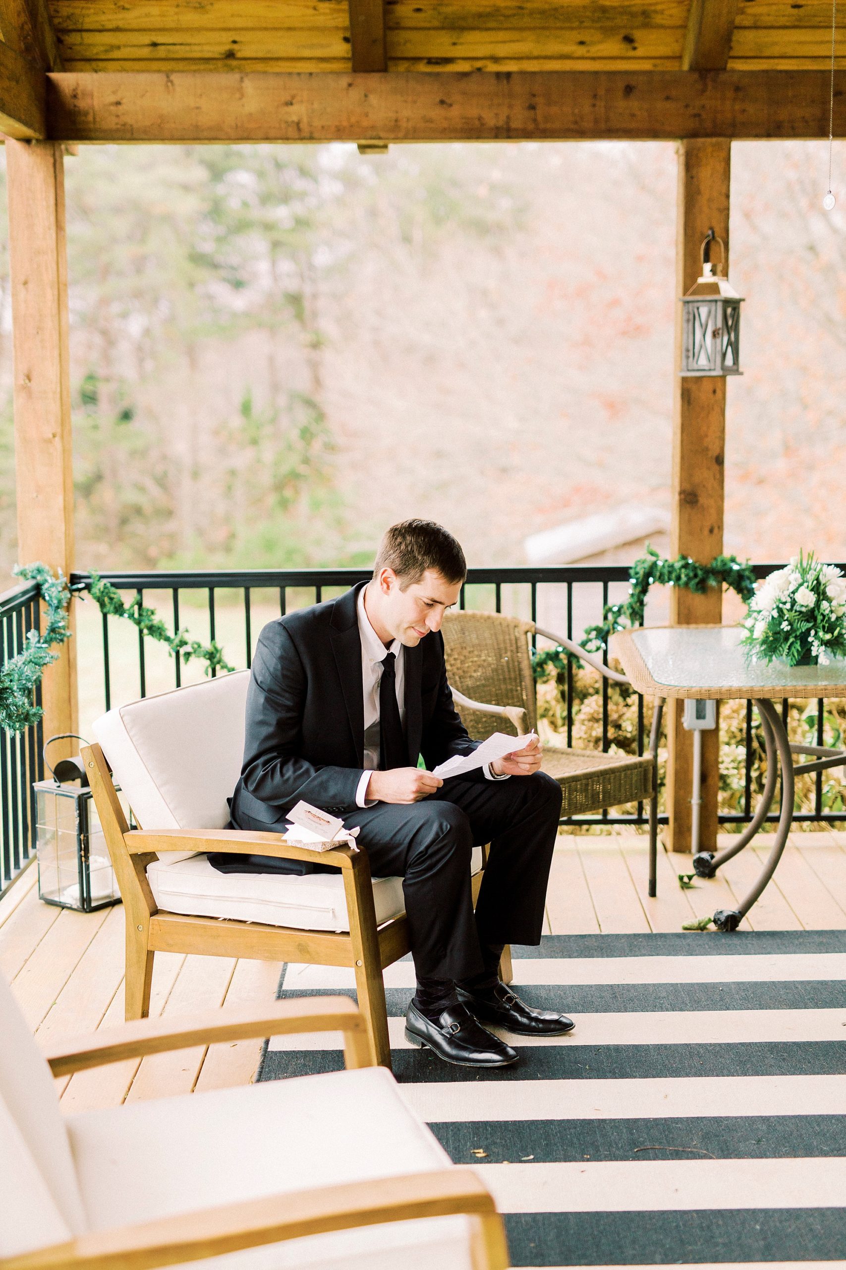 groom reads letter on porch before wedding day
