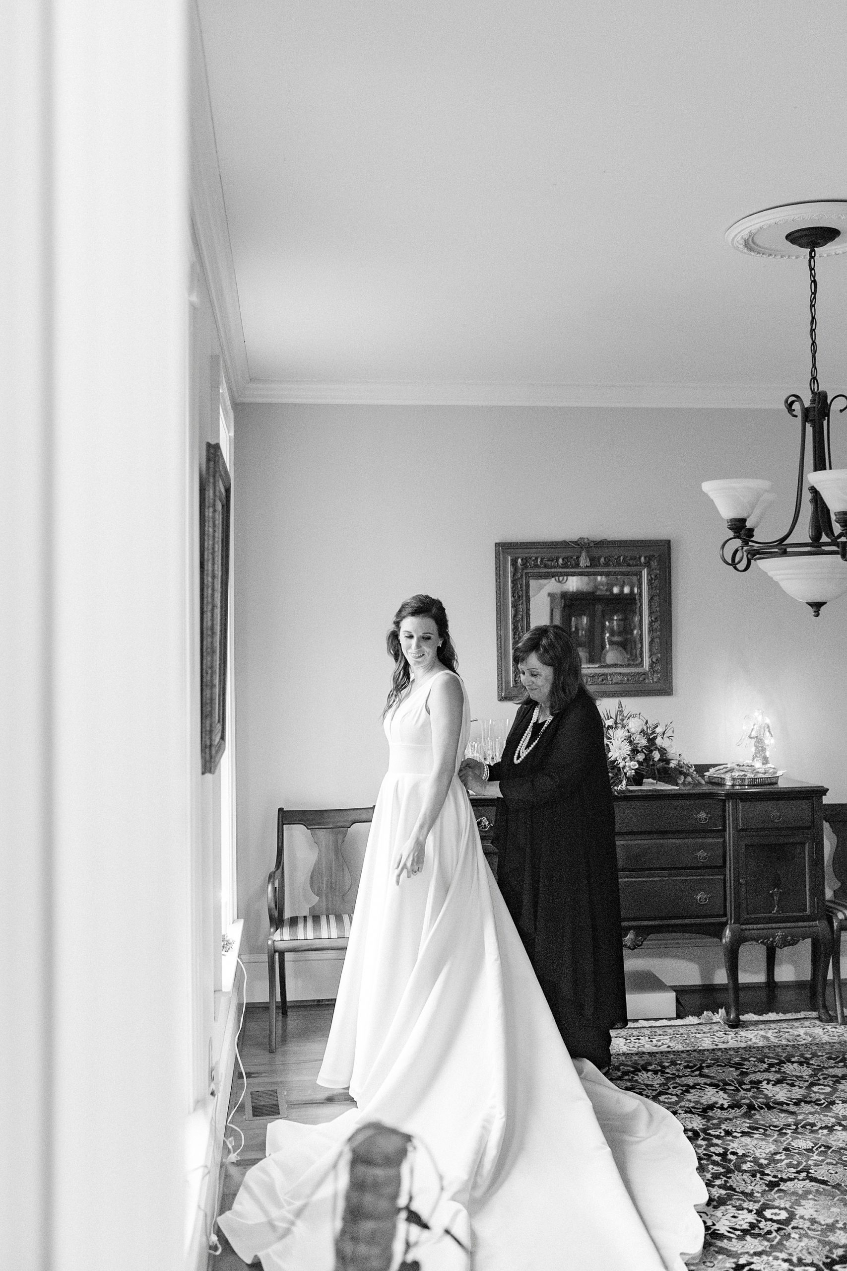 mother helps bride with wedding dress before romantic winter wedding in Bedford VA