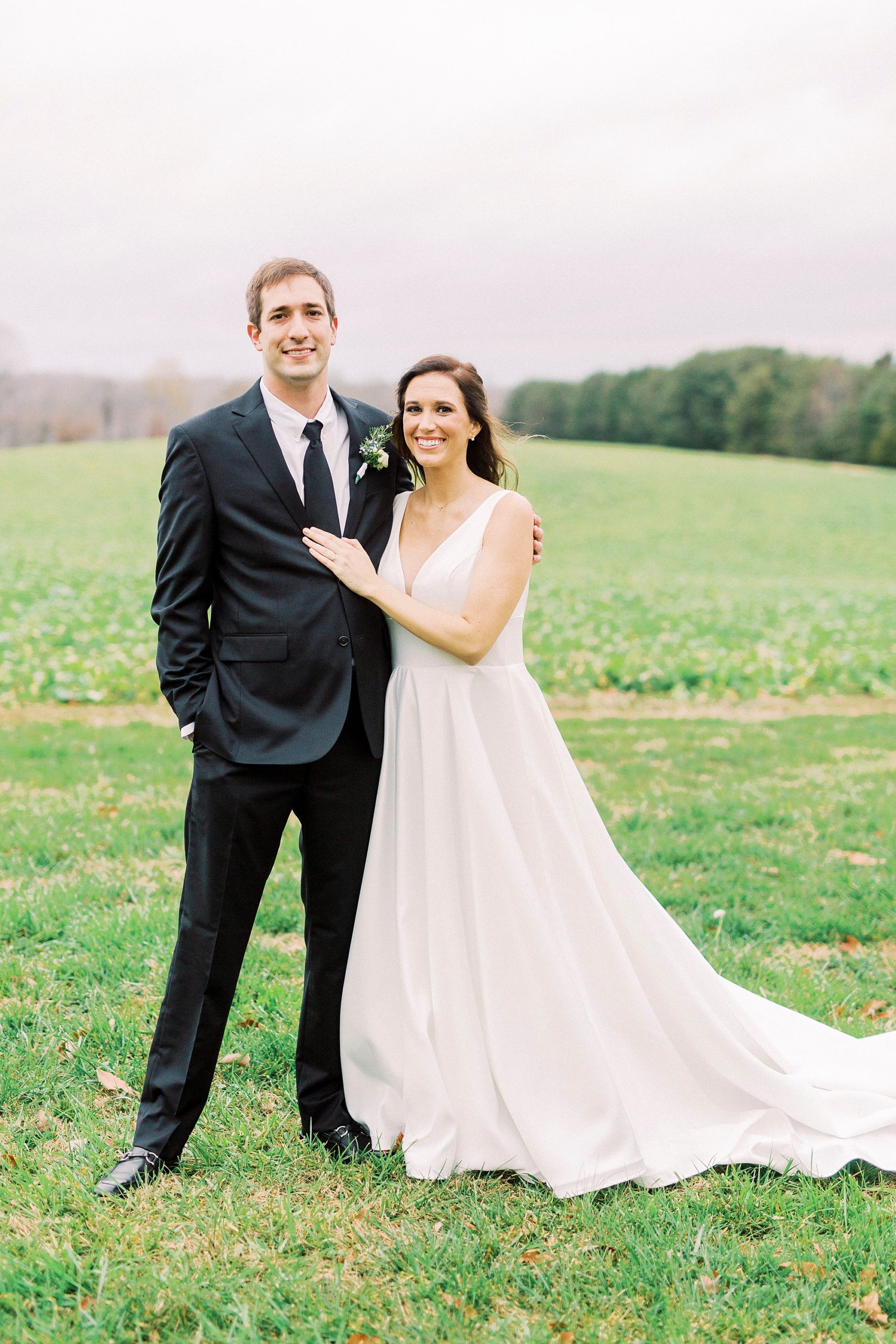 bride and groom pose in field during portraits in Bedford VA