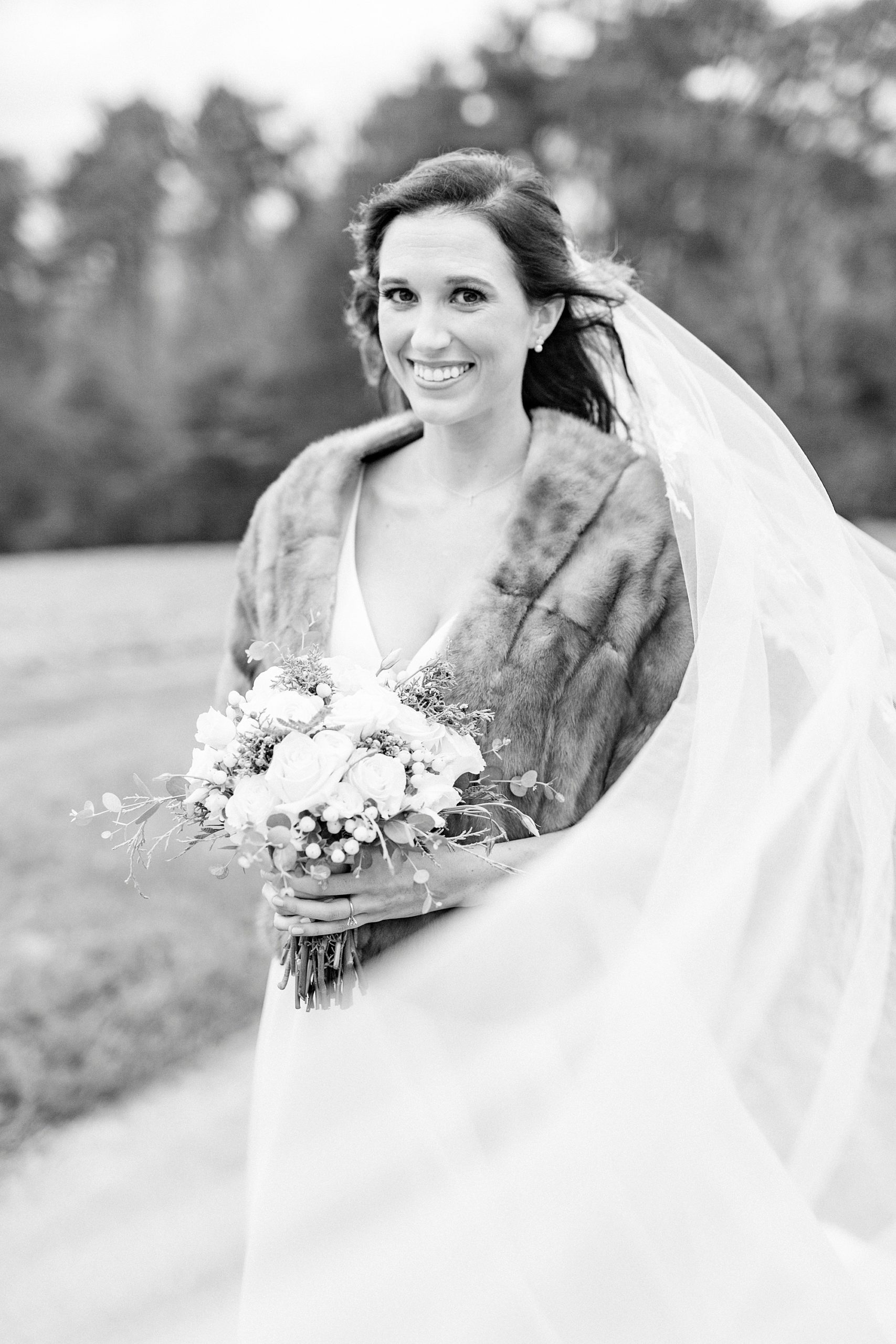 winter bride holds bouquet with fur wrap