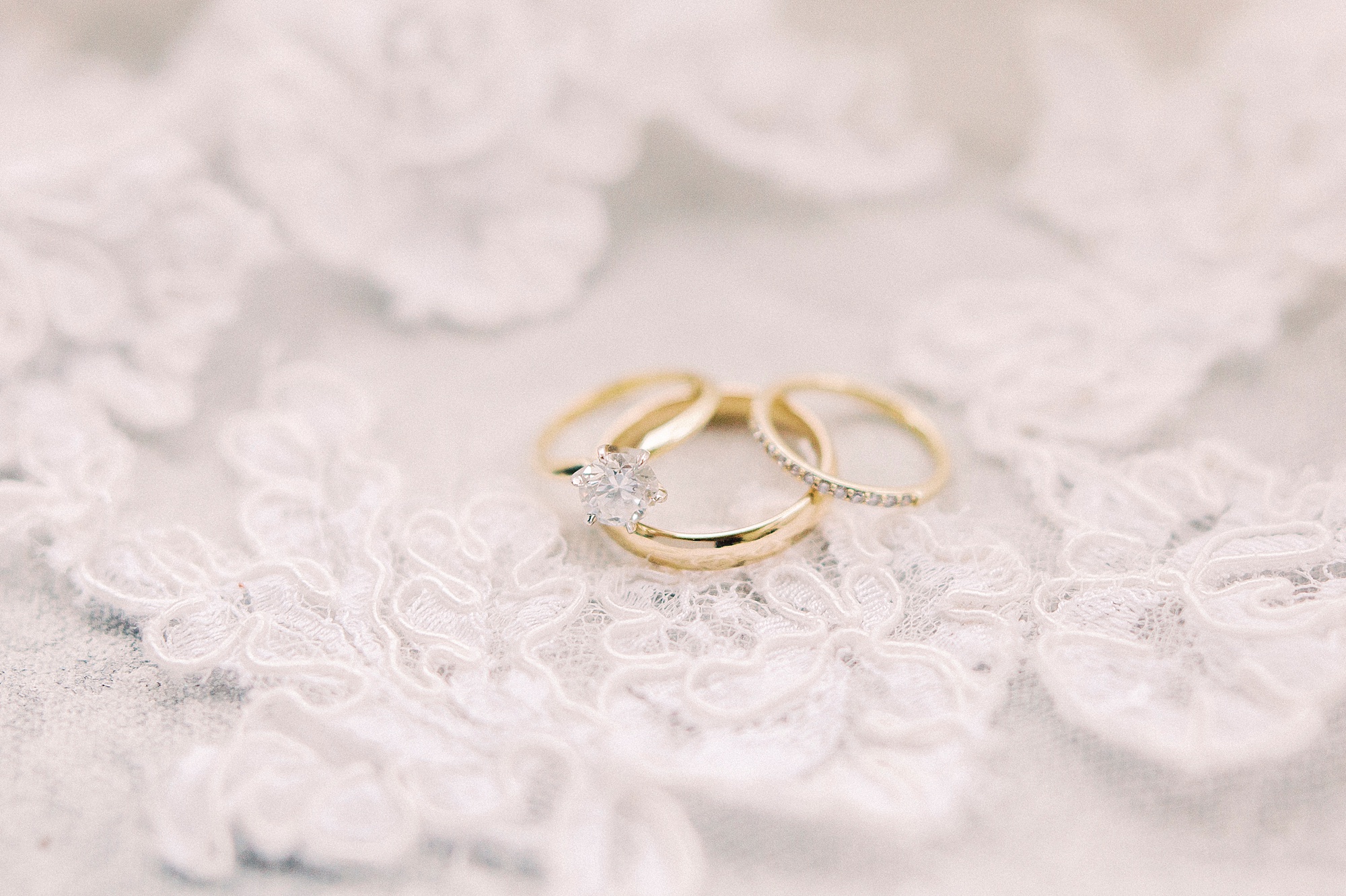 gold wedding bands lay on lace of veil