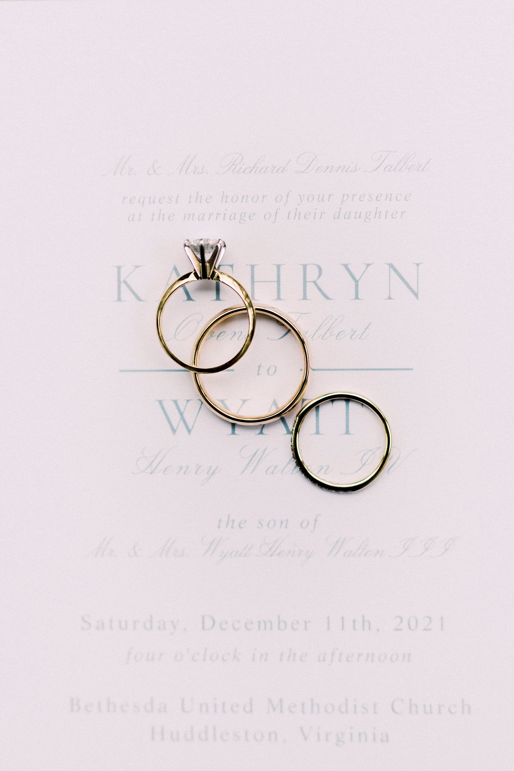 gold wedding bands rest on invitation suite for romantic winter wedding in Bedford VA