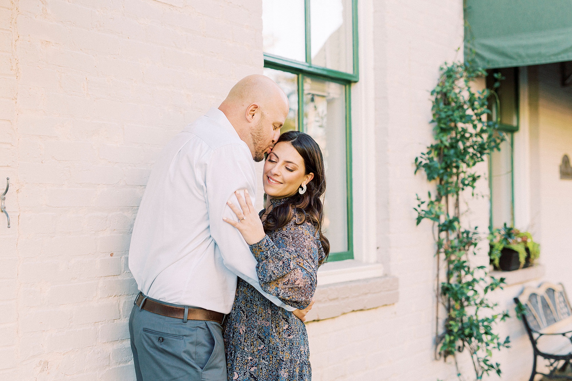 engaged couple hugs by pink wall during Downtown Matthews engagement session