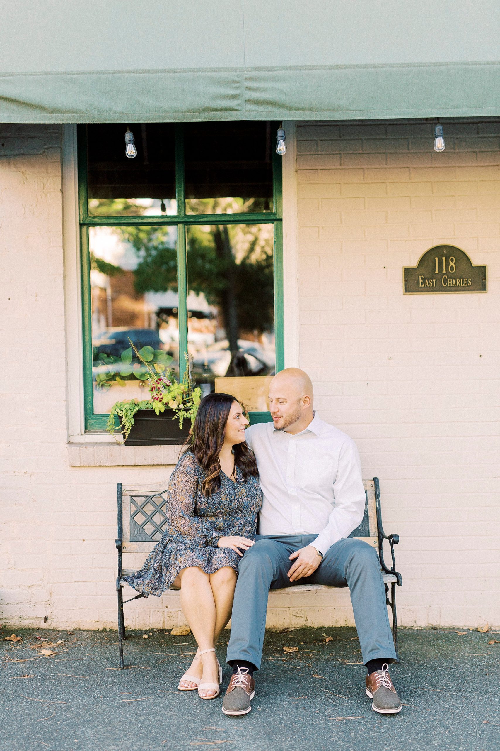 bride and groom sit on bench by coffee shop in Downtown Matthews
