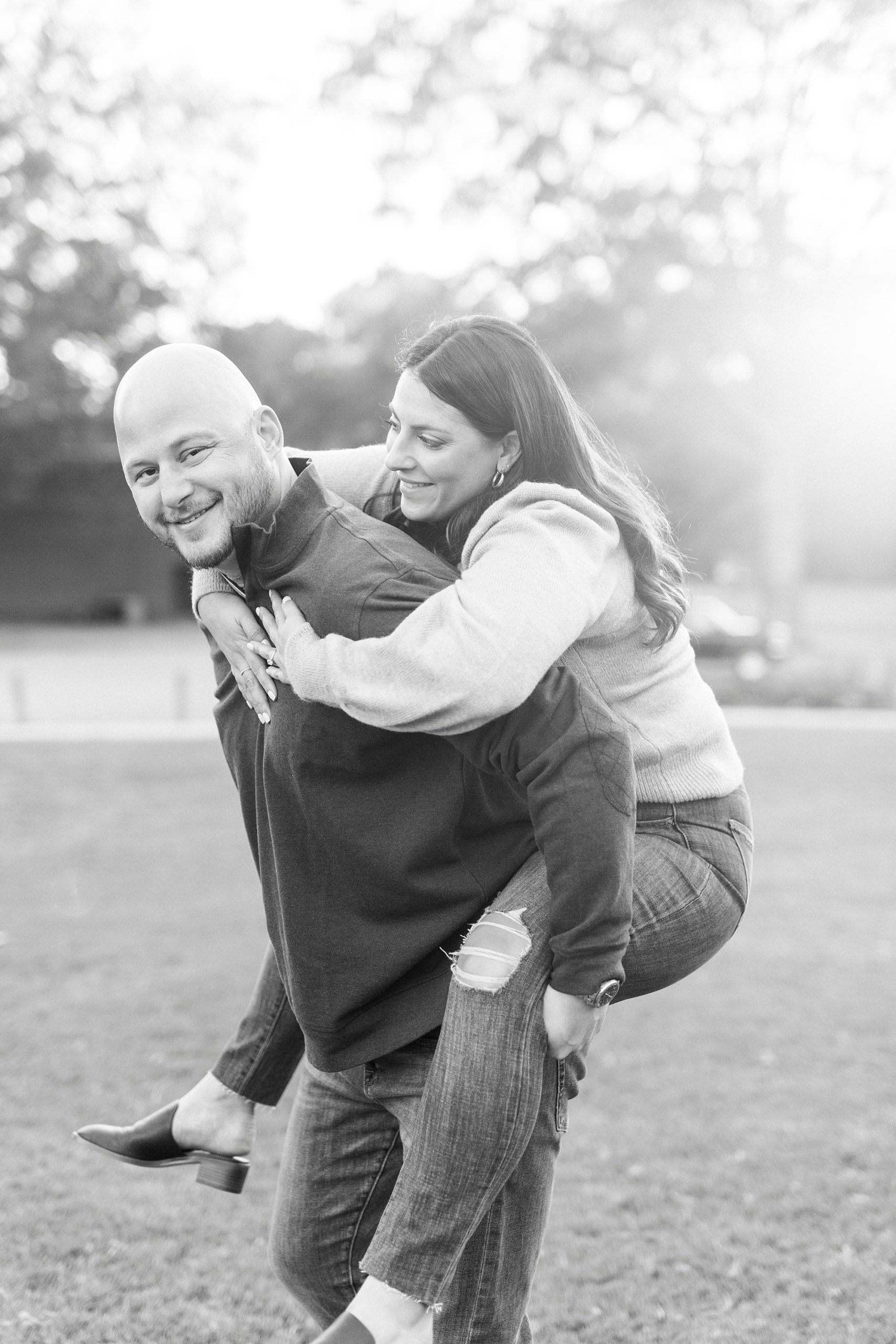 groom gives bride piggy back ride during Downtown Matthews engagement photos