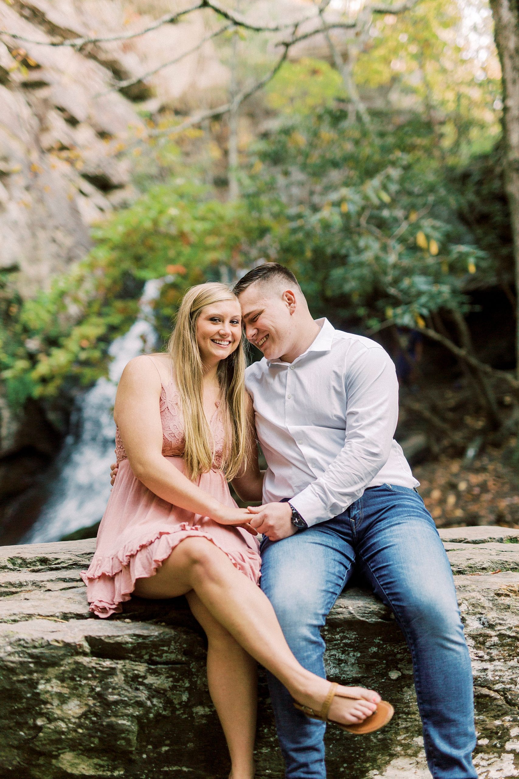 bride and groom sit on rocks by waterfall at Hanging Rock State Park