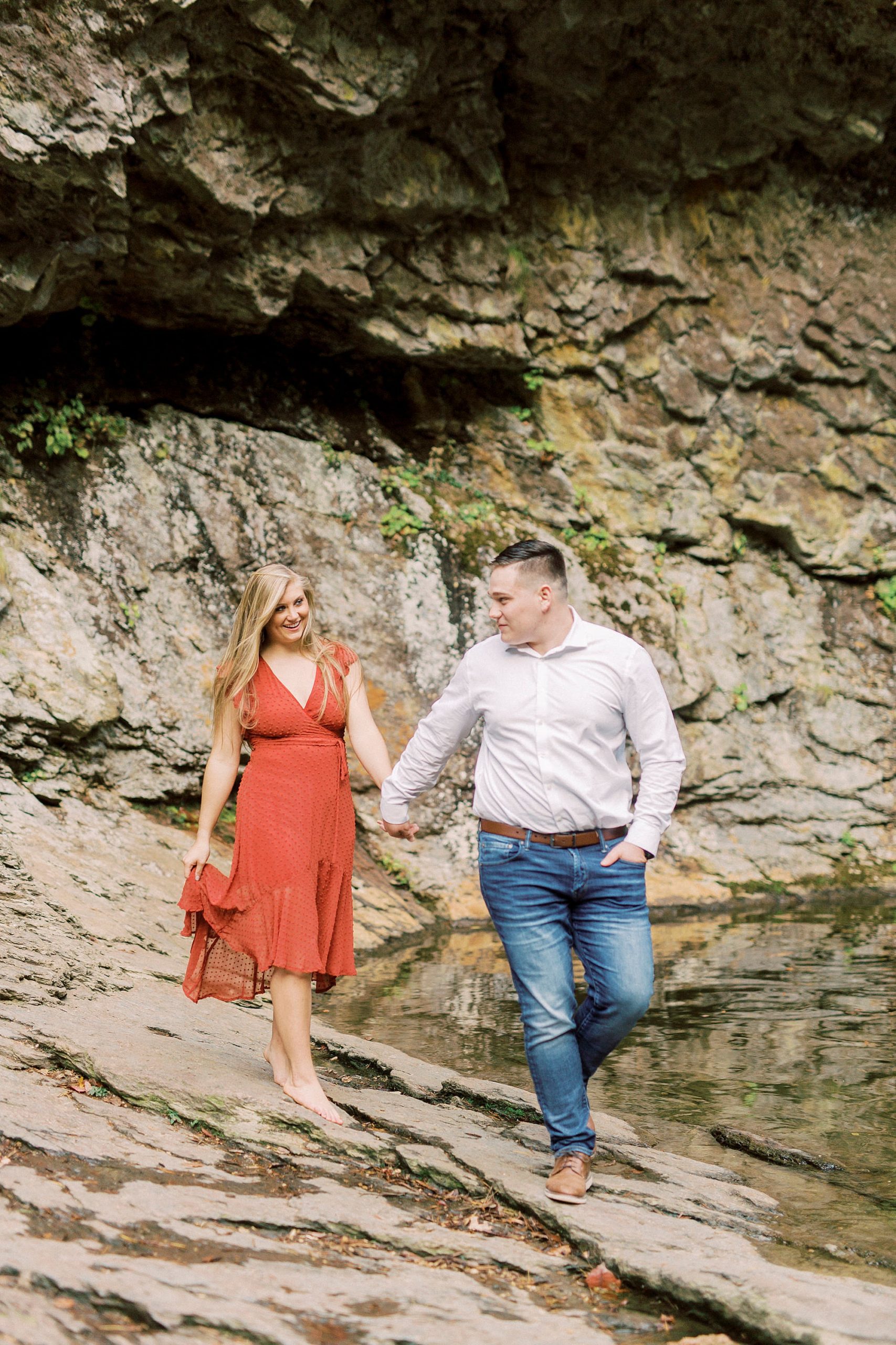 groom leads bride through rocks during NC engagement photos