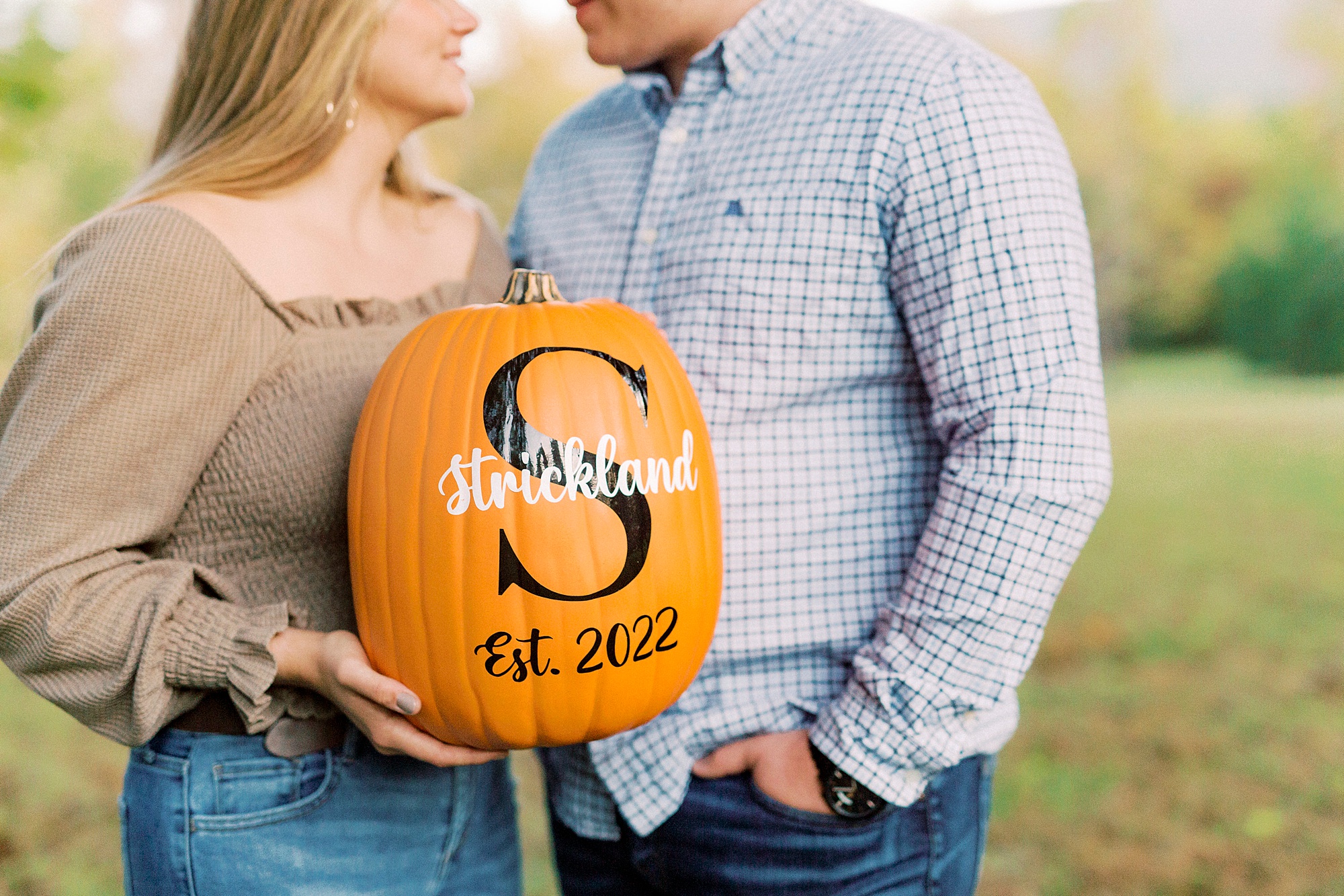 couple holds pumpkin with save the date information