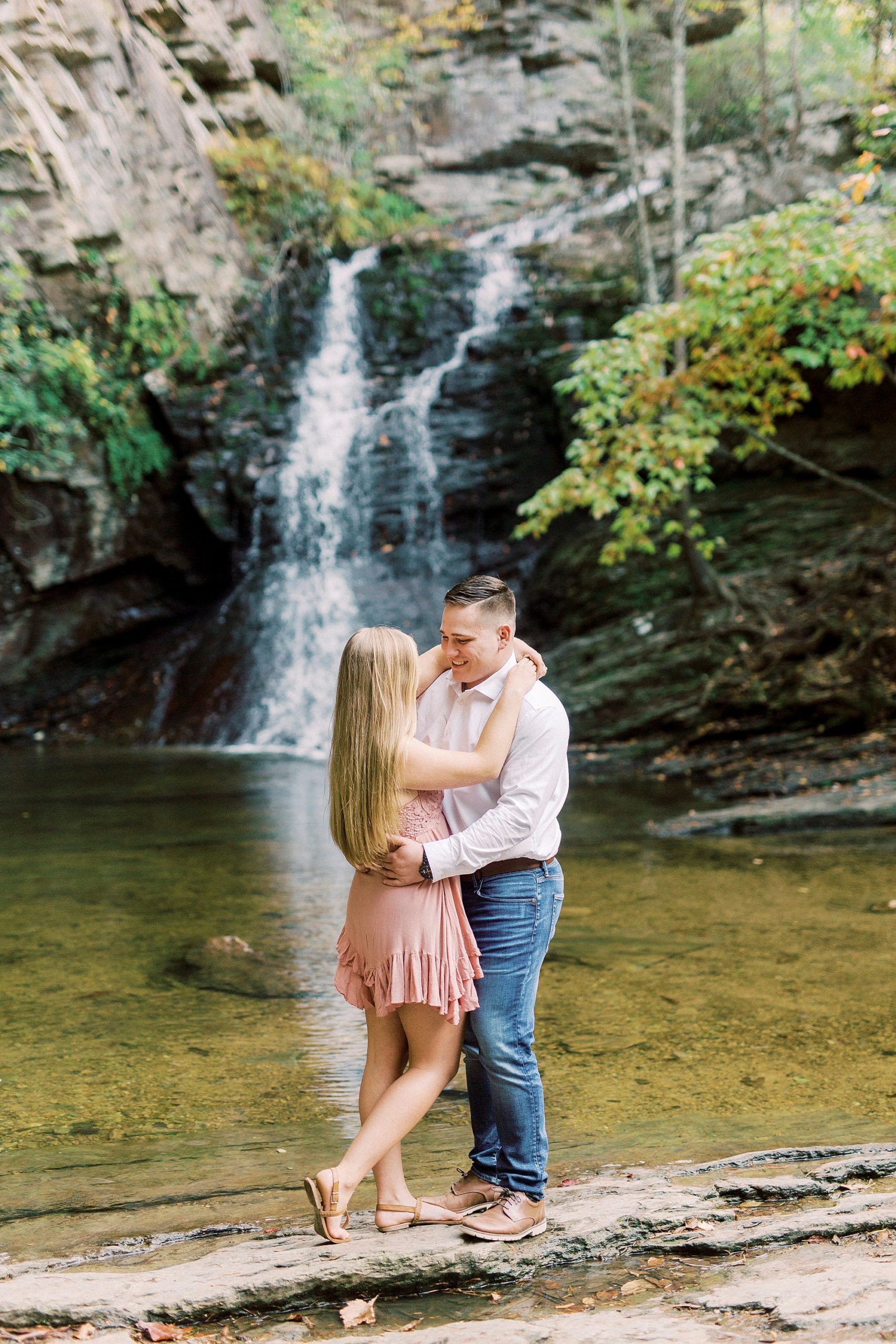 bride and groom hug in front of waterfall in Hanging Rock State Park