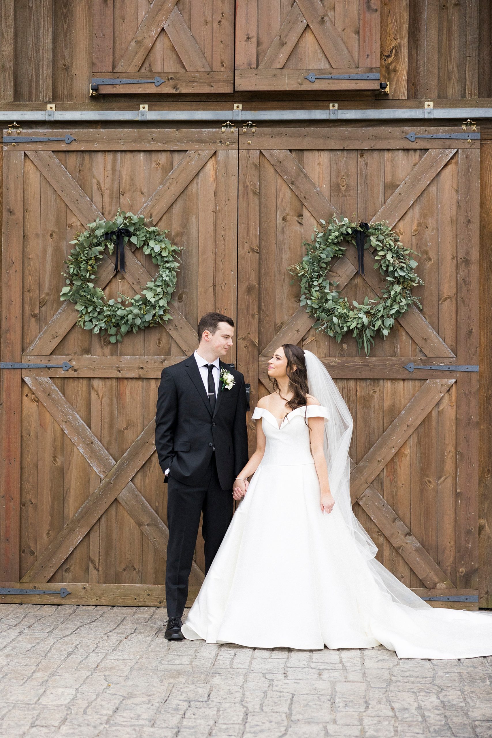 bride and groom hold hands outside barn doors at The Farm at Brusharbor