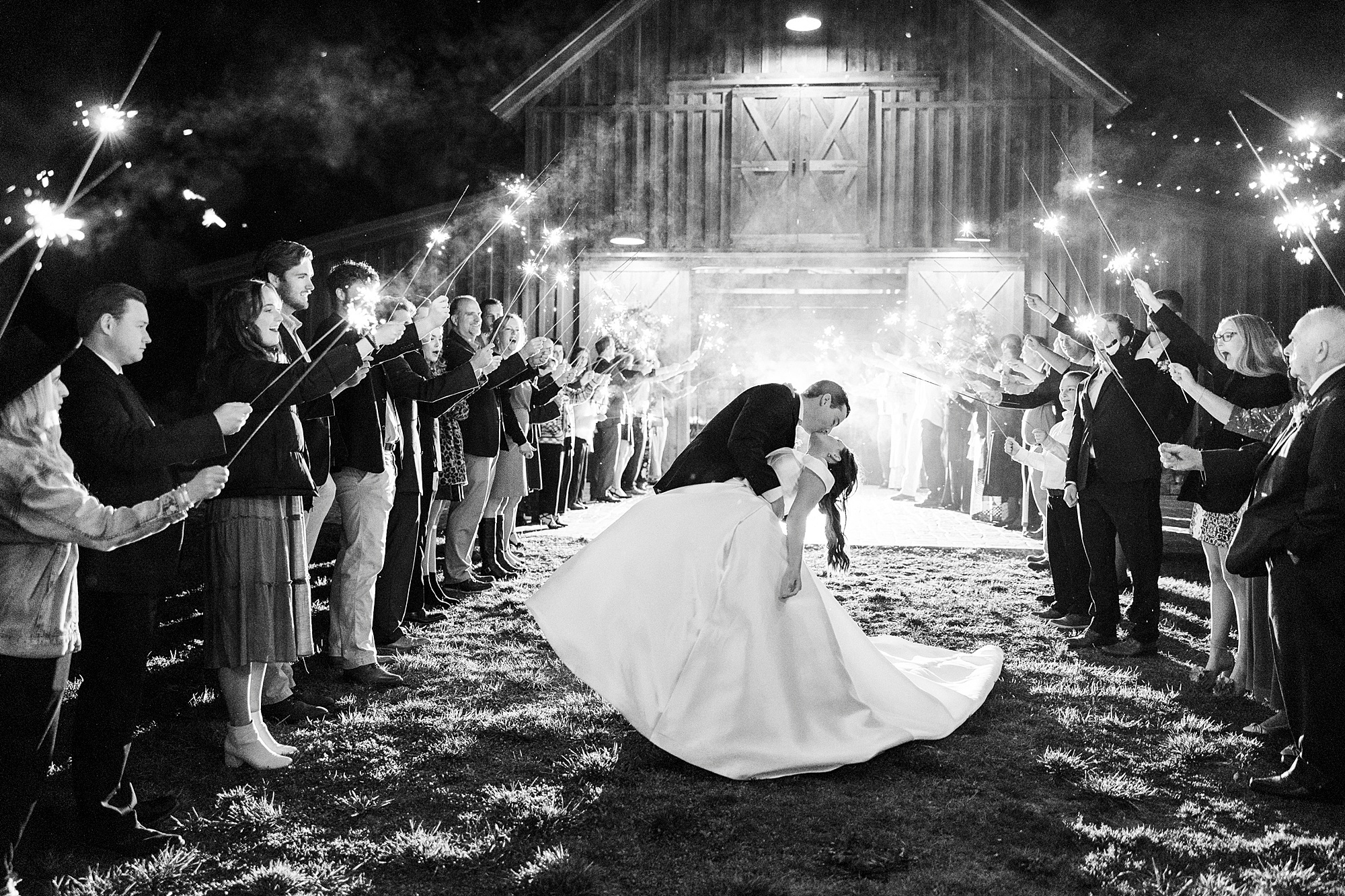 groom kisses bride dipping her during sparkler exit